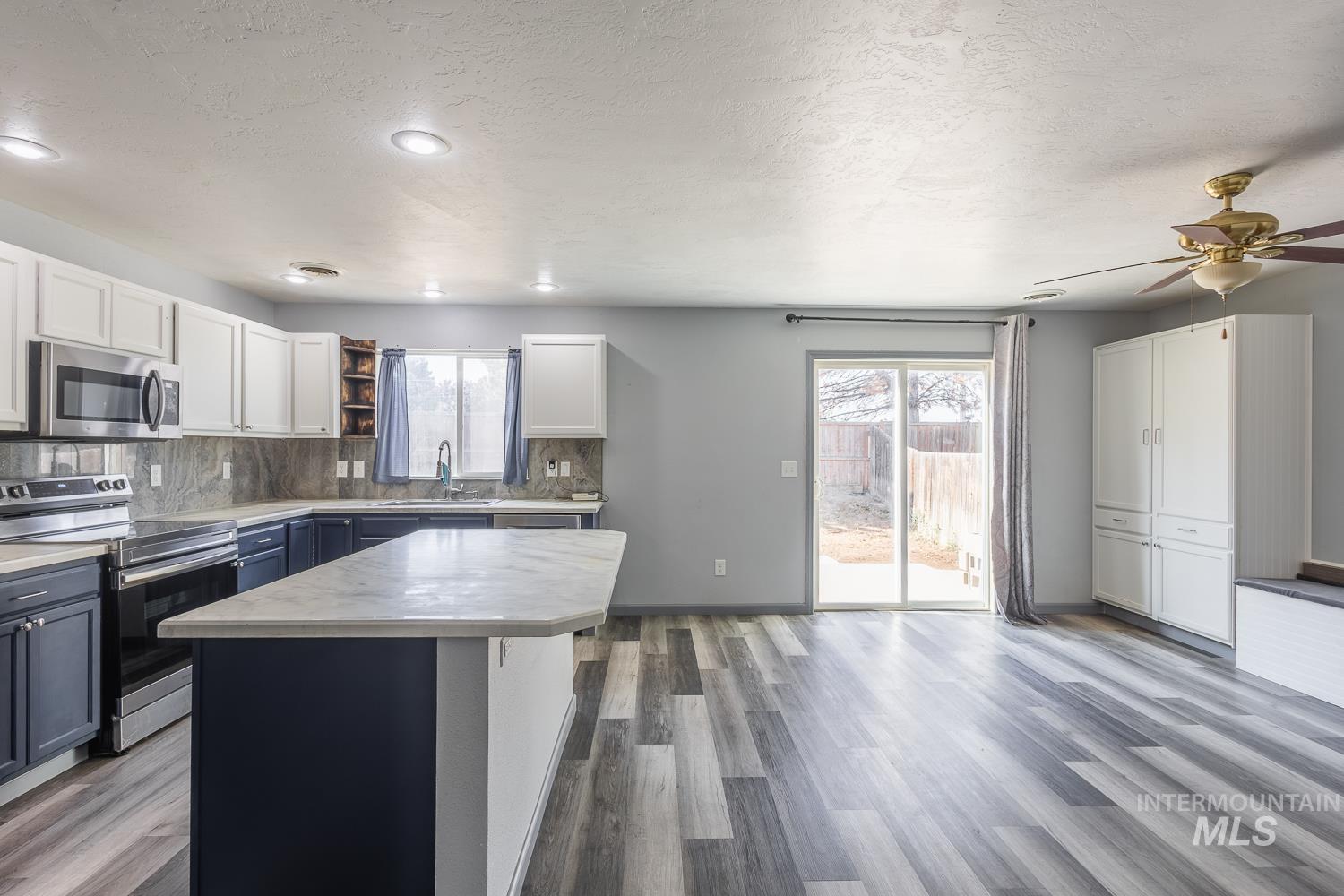 Kitchen featuring appliances with stainless steel finishes, plenty of natural light, white cabinetry, a textured ceiling, and decorative backsplash