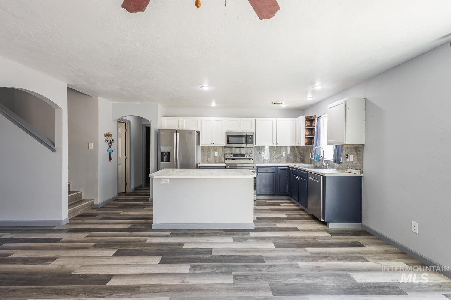 Kitchen with white cabinetry, a ceiling fan, appliances with stainless steel finishes, and light wood-type flooring