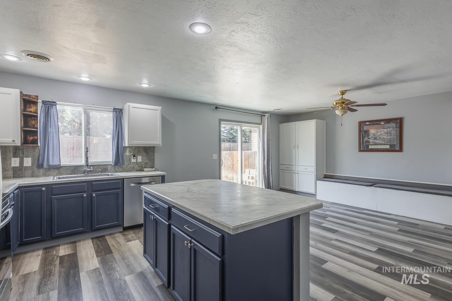 Kitchen featuring healthy amount of natural light, backsplash, a textured ceiling, appliances with stainless steel finishes, and dark wood finished floors