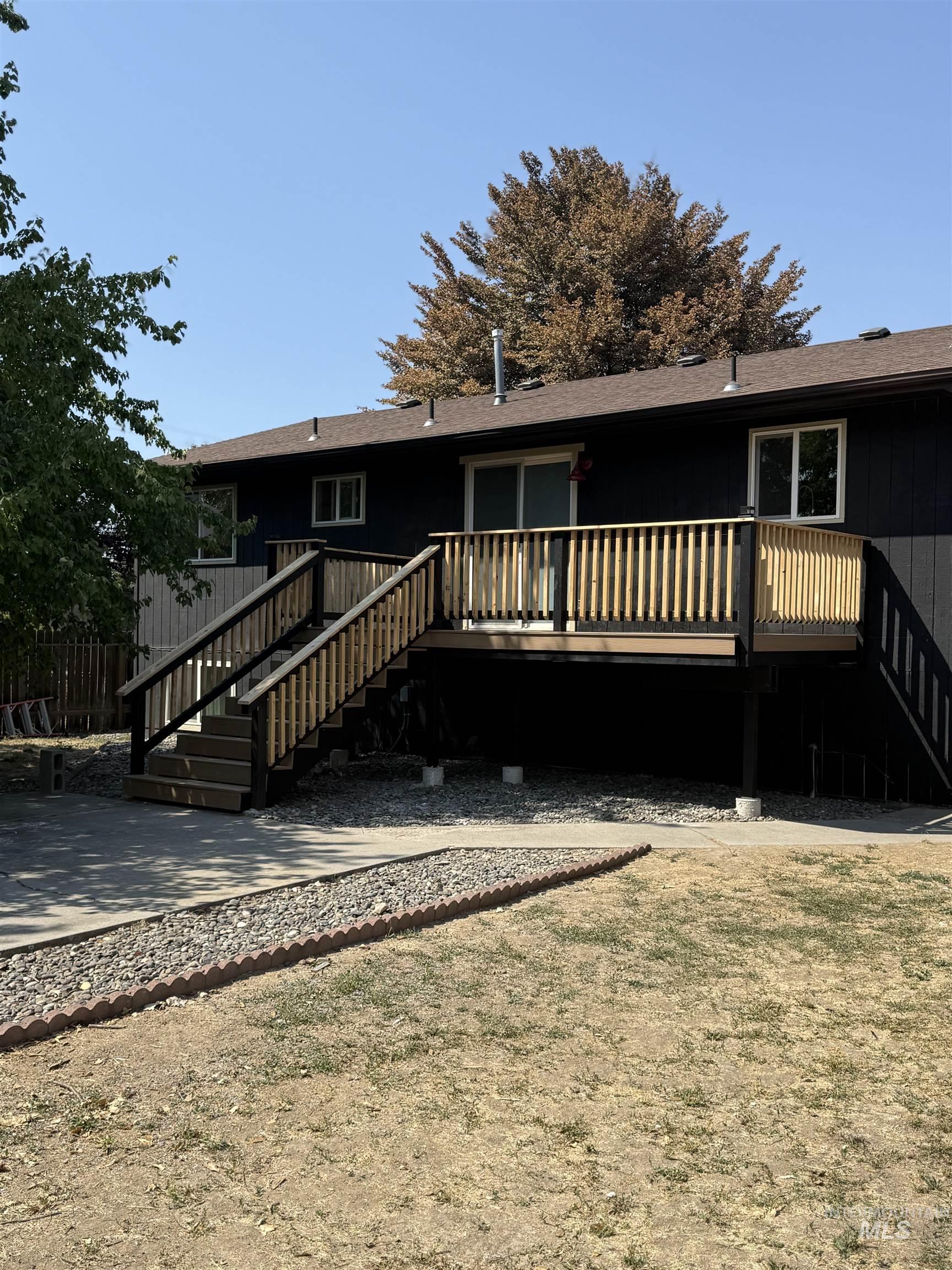 Rear view of house featuring stairs, a deck, a lawn, and roof with shingles