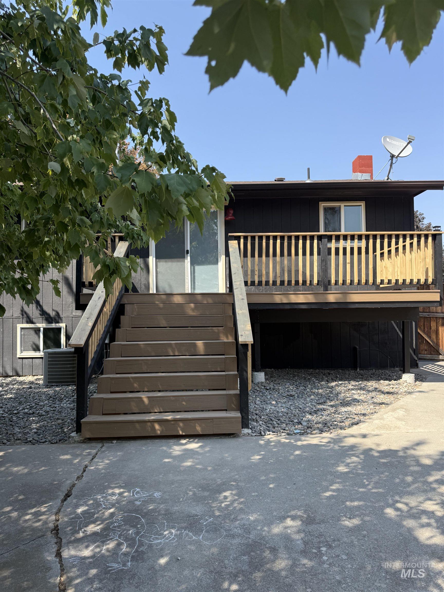 View of front facade featuring stairway, a deck, board and batten siding, and a chimney