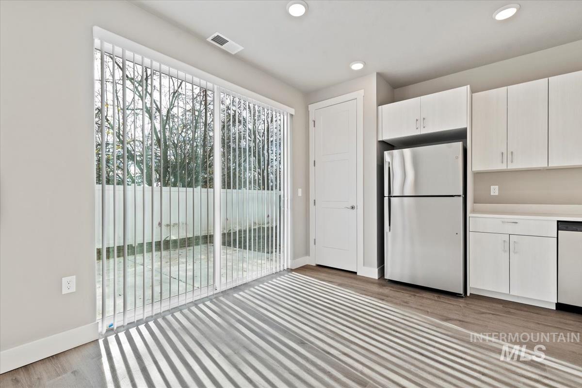 Kitchen with freestanding refrigerator, white cabinetry, light countertops, dishwashing machine, and recessed lighting