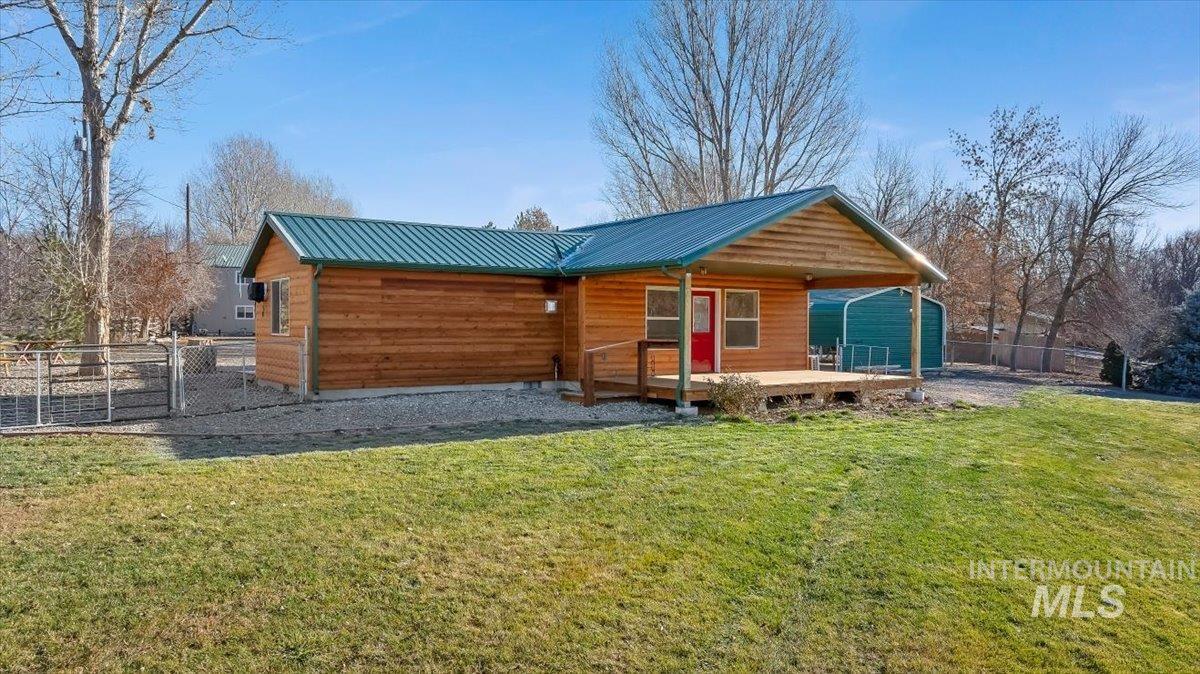 View of front of house with a metal roof, a gate, and a wooden deck