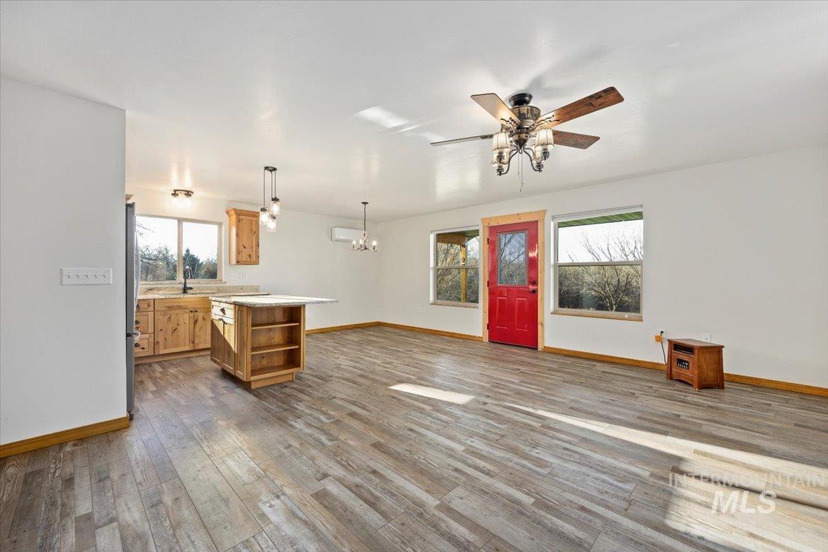 Unfurnished living room featuring dark wood finished floors, a ceiling fan, and a chandelier