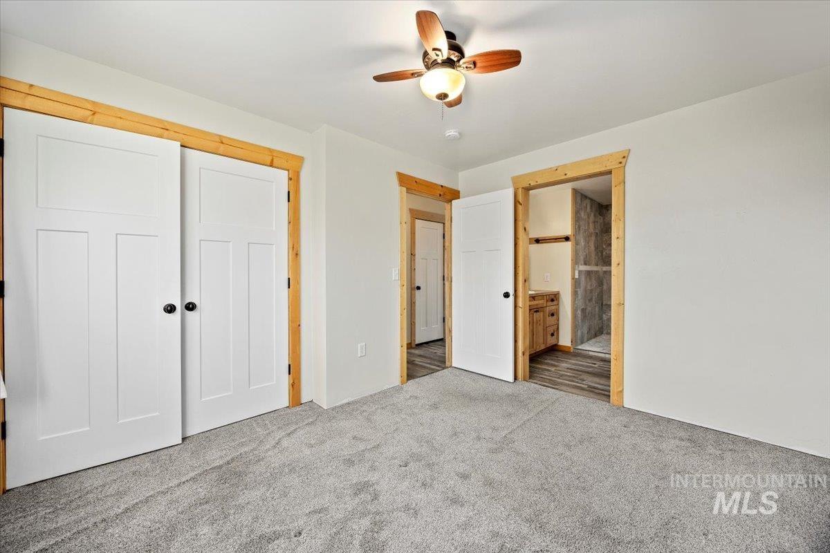 Unfurnished bedroom with a closet, connected bathroom, ceiling fan, and carpet floors