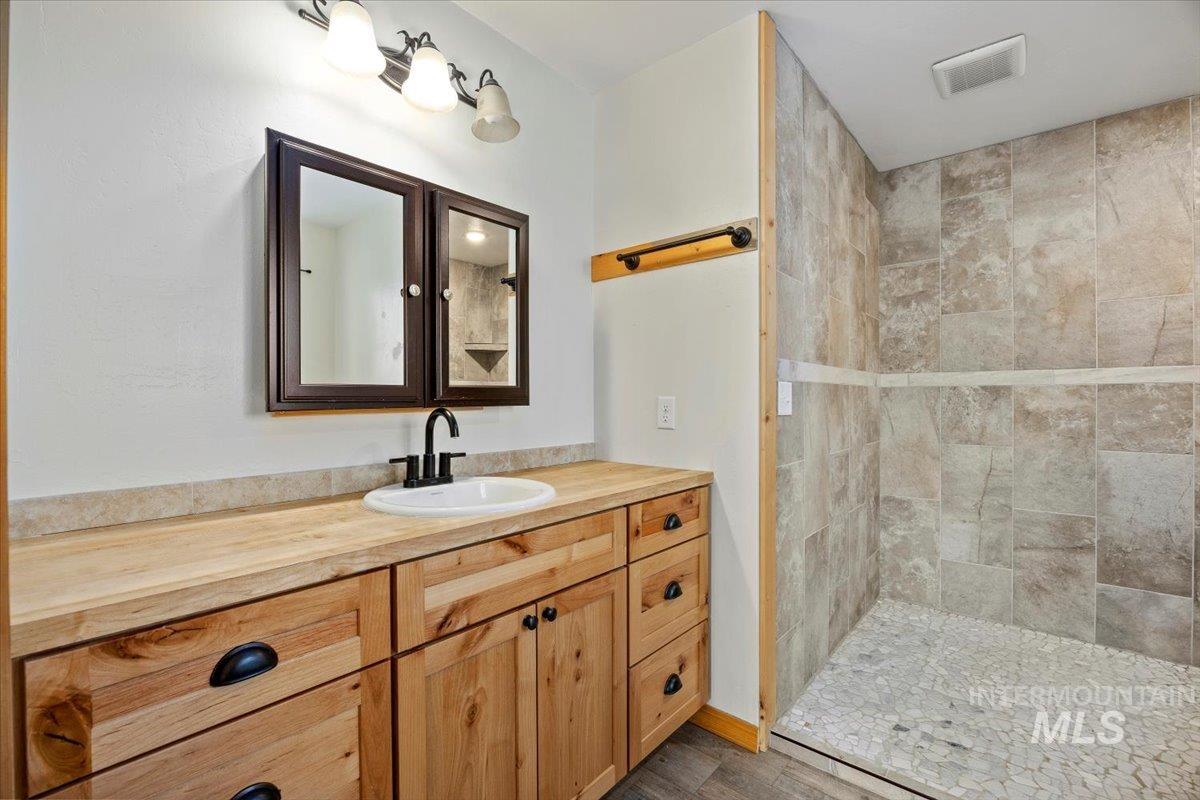 Bathroom with vanity and tiled shower