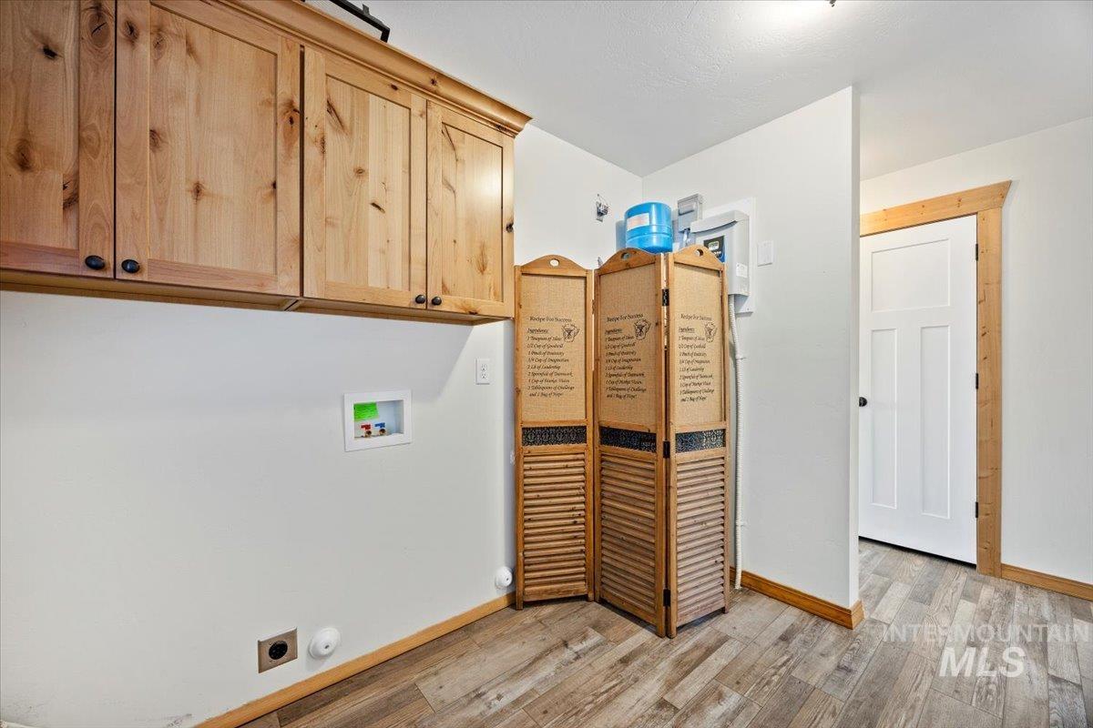 Laundry area featuring light wood-style flooring, hookup for a washing machine, cabinet space, and gas dryer hookup