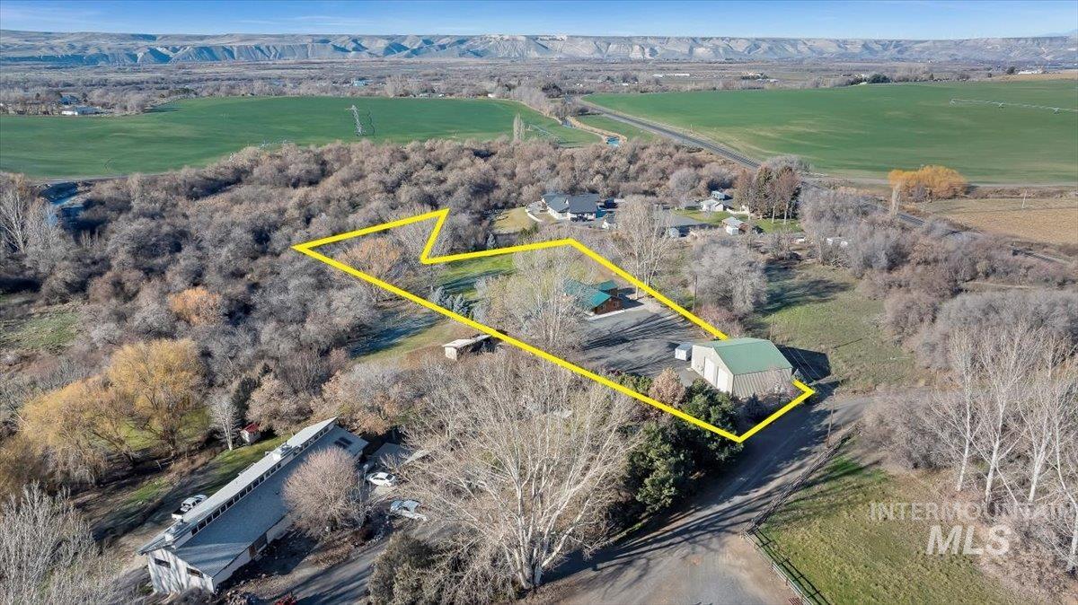 Aerial view of property and surrounding area with property parcel outlined and a mountainous background