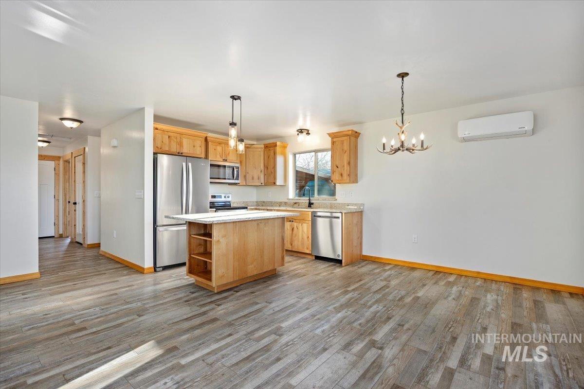 Kitchen featuring appliances with stainless steel finishes, a center island, decorative light fixtures, a chandelier, and open shelves