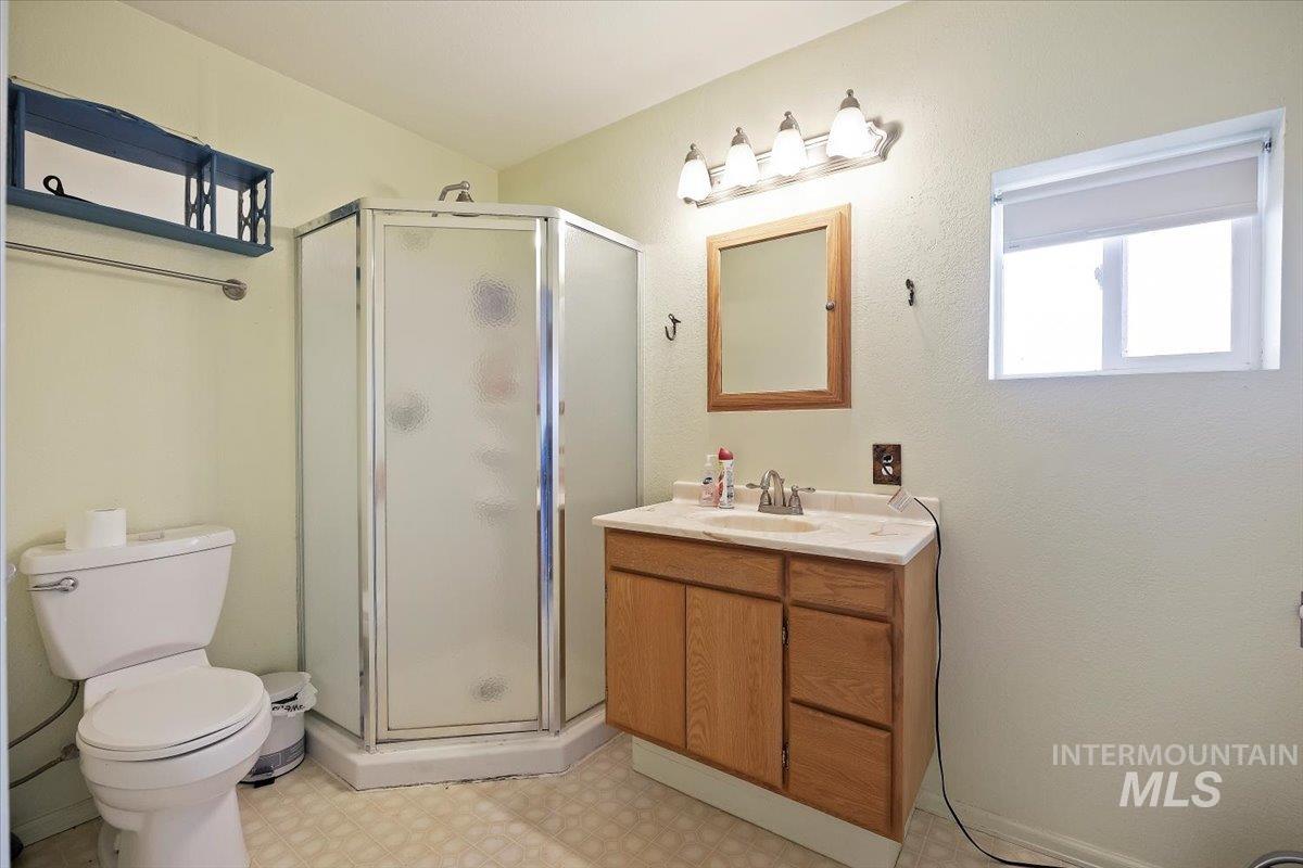Bathroom with light floors, a stall shower, and vanity