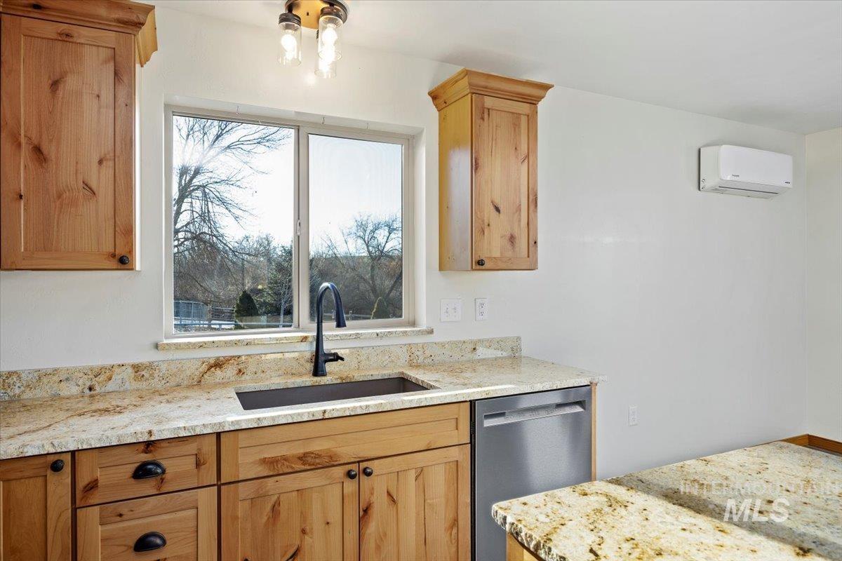 Kitchen with light stone countertops, dishwasher, light brown cabinetry, and an AC wall unit