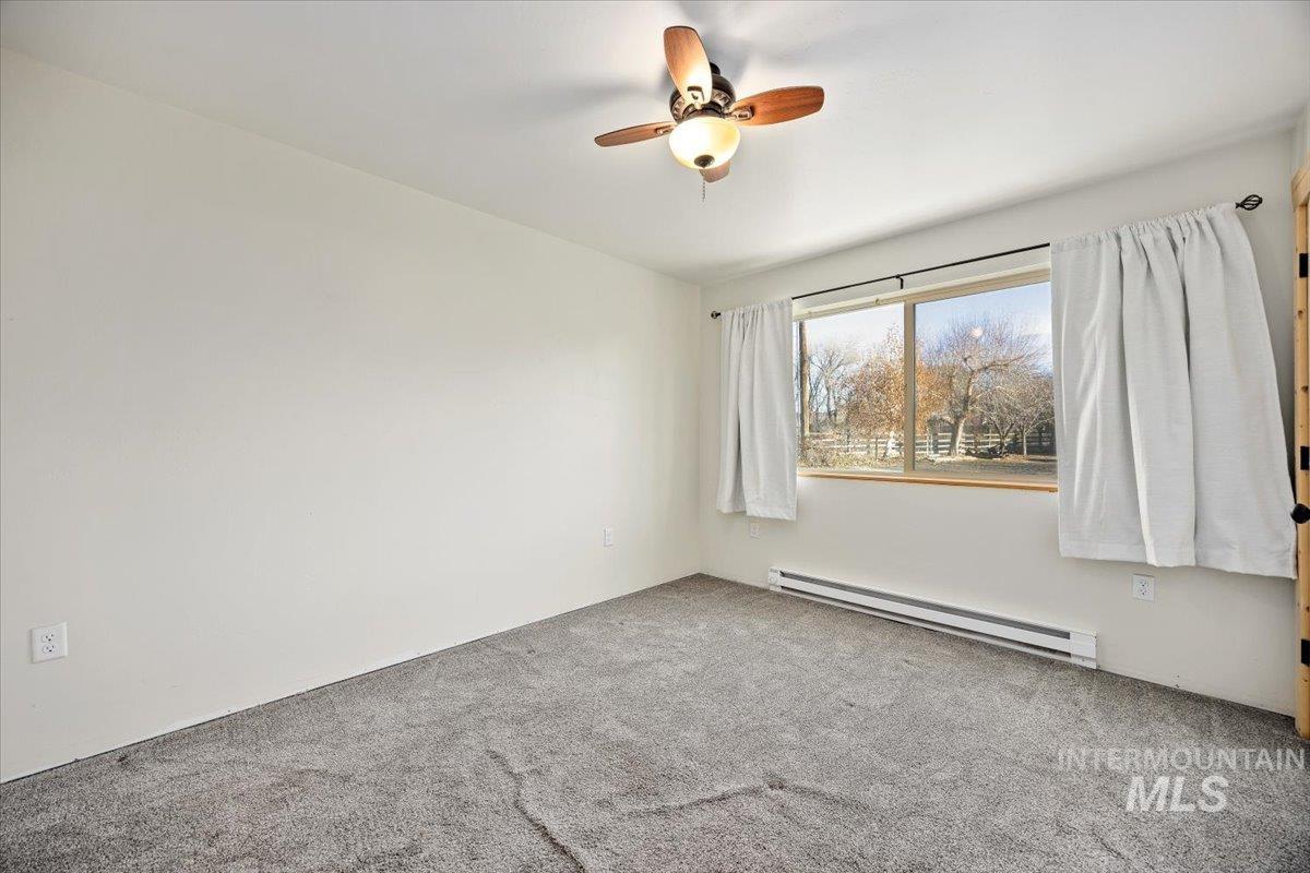 Spare room with baseboard heating, carpet, and ceiling fan