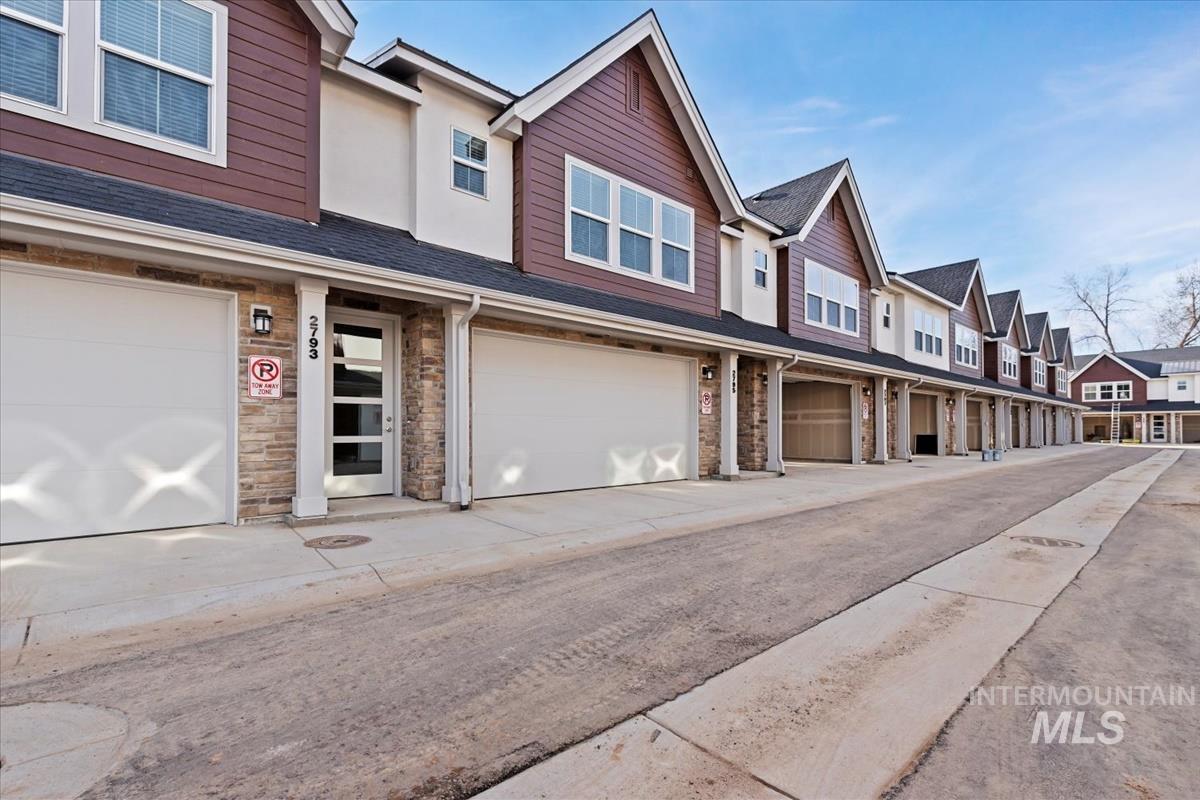 View of front of property with a residential view, stone siding, roof with shingles, and an attached garage