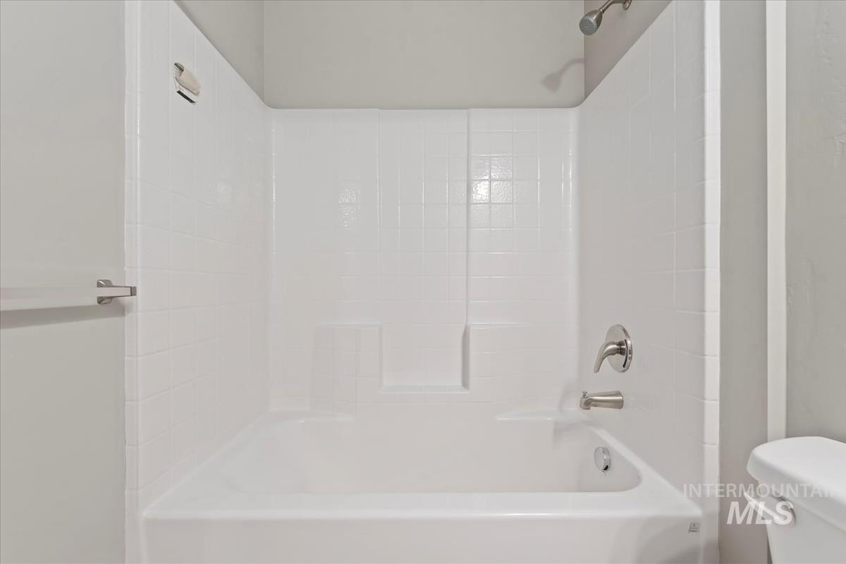 Full bathroom featuring toilet and washtub / shower combination