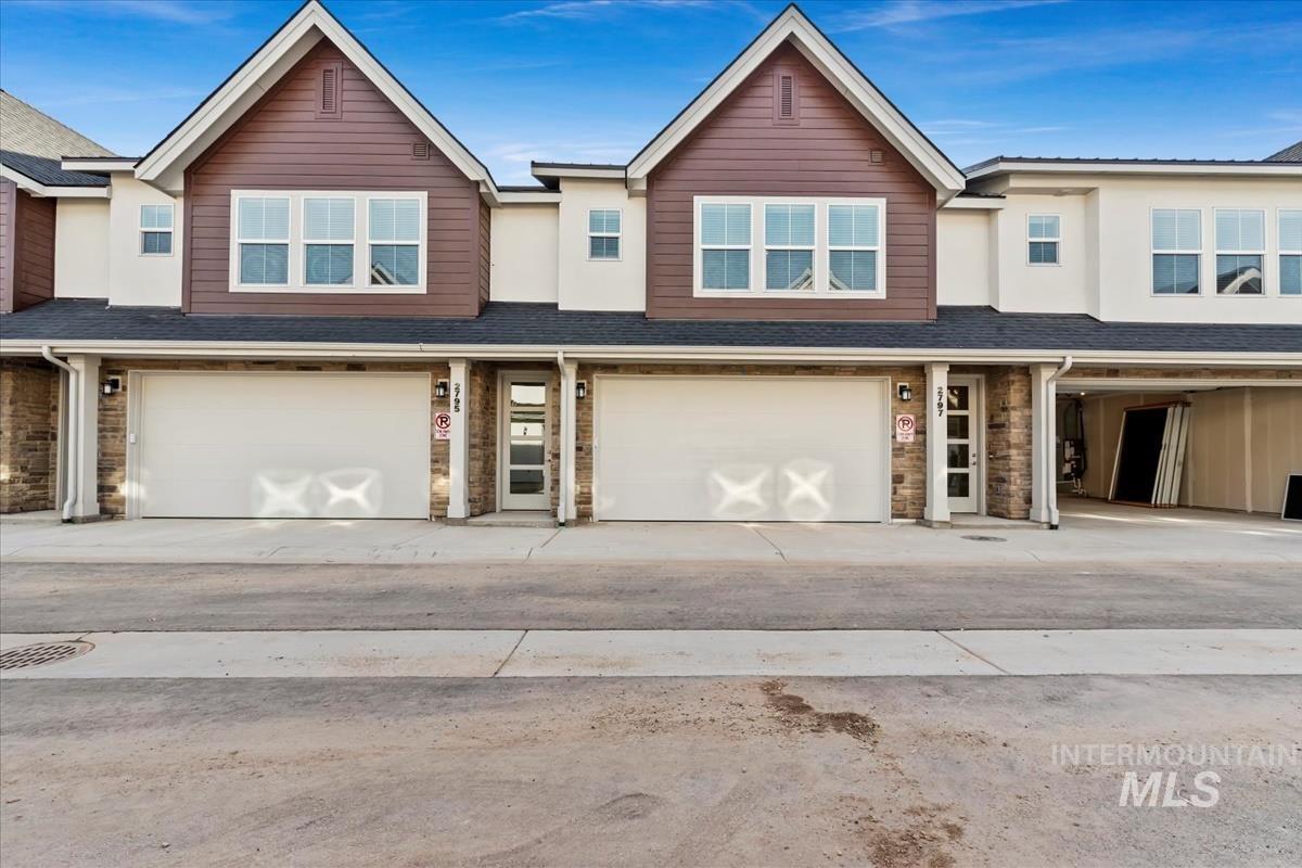 View of front of property with stone siding, a shingled roof, a garage, and concrete driveway