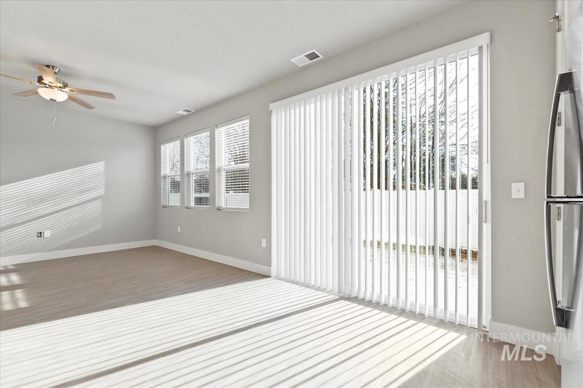 Unfurnished room featuring a ceiling fan, light wood-type flooring, and lofted ceiling
