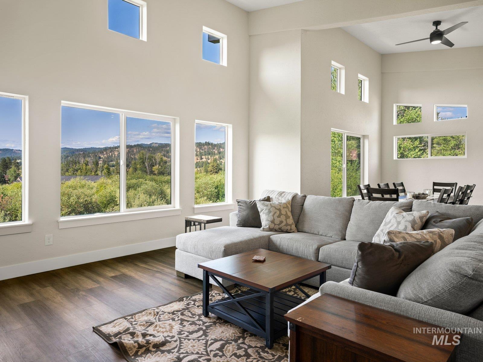 Living room with a ceiling fan, high ceiling, and abundant natural light
