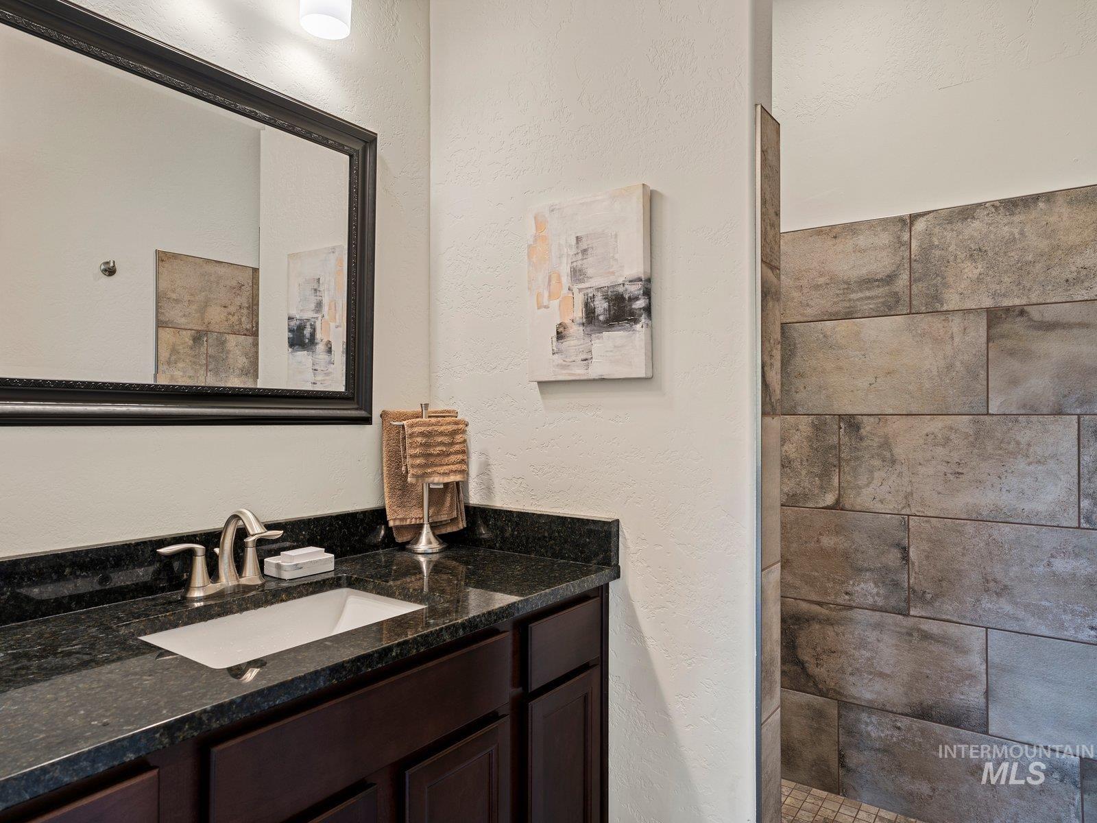 Bathroom on main level with vanity, and tiled shower