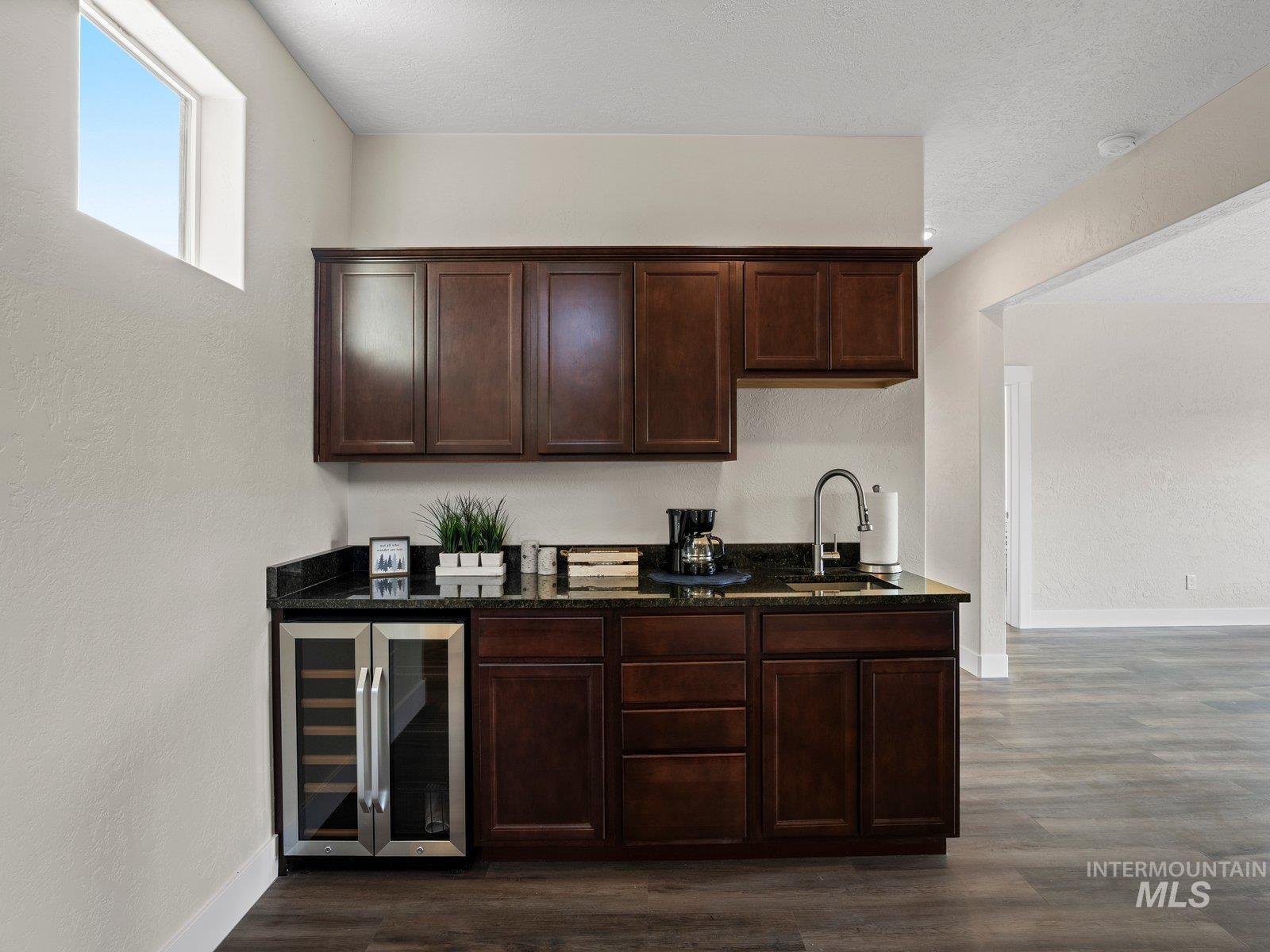Bar area featuring beverage cooler, dark granite countertops, could be converted into second kitchenette