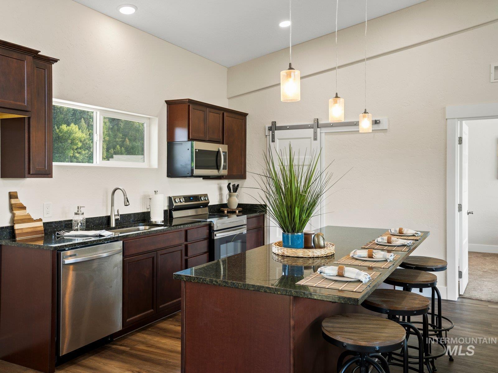 Kitchen featuring a barn door to pantry, appliances with stainless steel finishes, granite counters