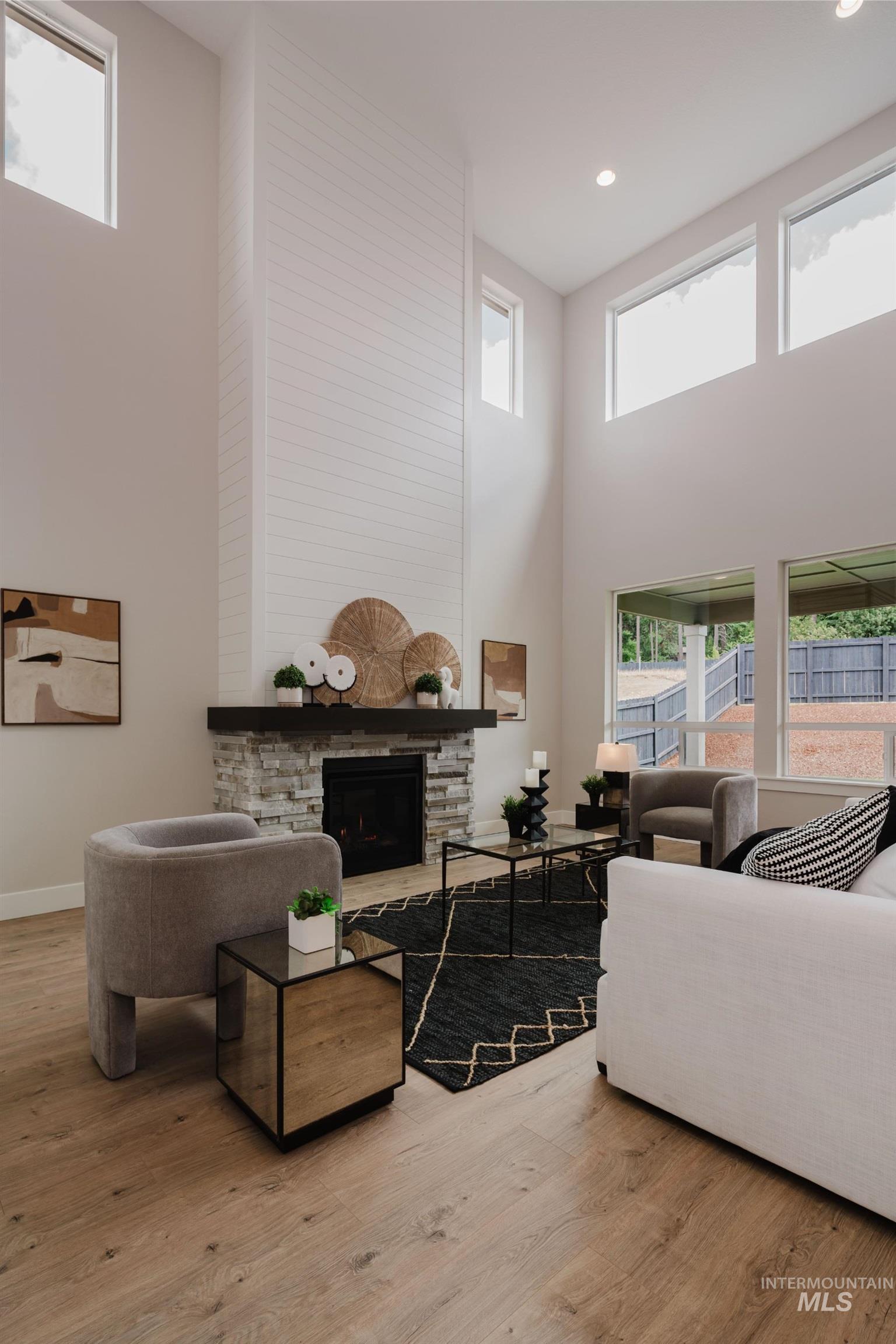Living area featuring a high ceiling, a fireplace, and light wood-style floors