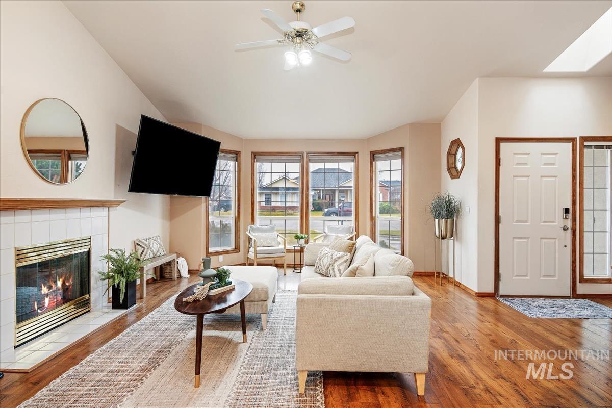 Living room with wood finished floors, a fireplace, and a ceiling fan