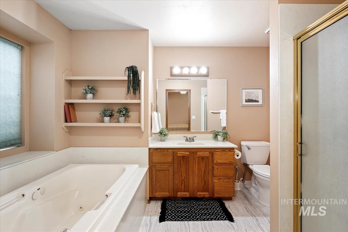 Full bathroom featuring a tub with jets, vanity, and a shower stall