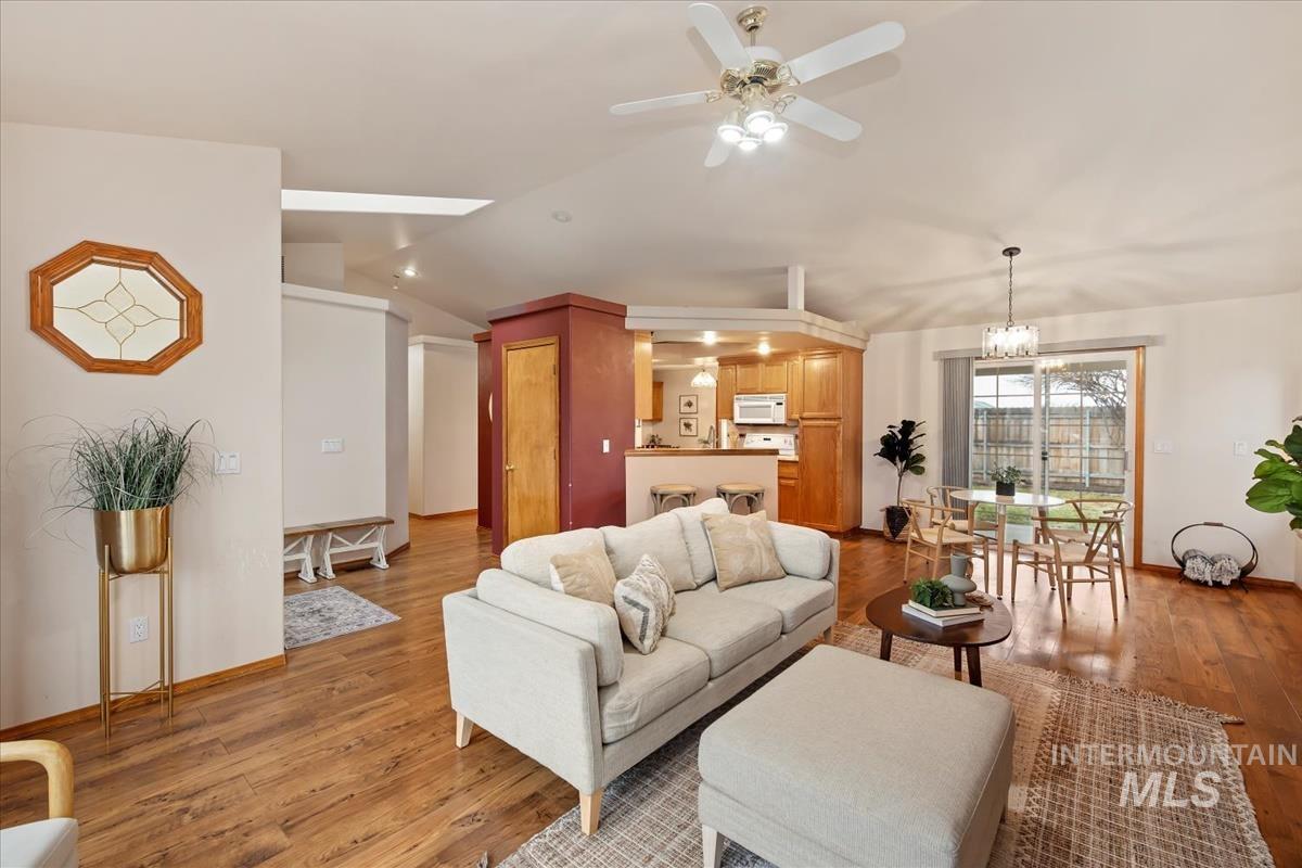 Living area with vaulted ceiling, light wood-type flooring, ceiling fan, and a chandelier