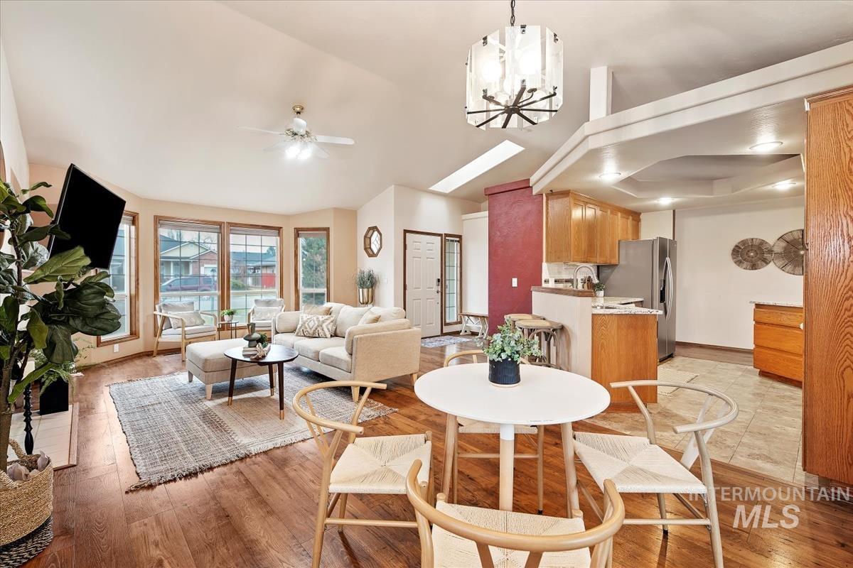 Dining room with a chandelier, light wood finished floors, ceiling fan, and lofted ceiling