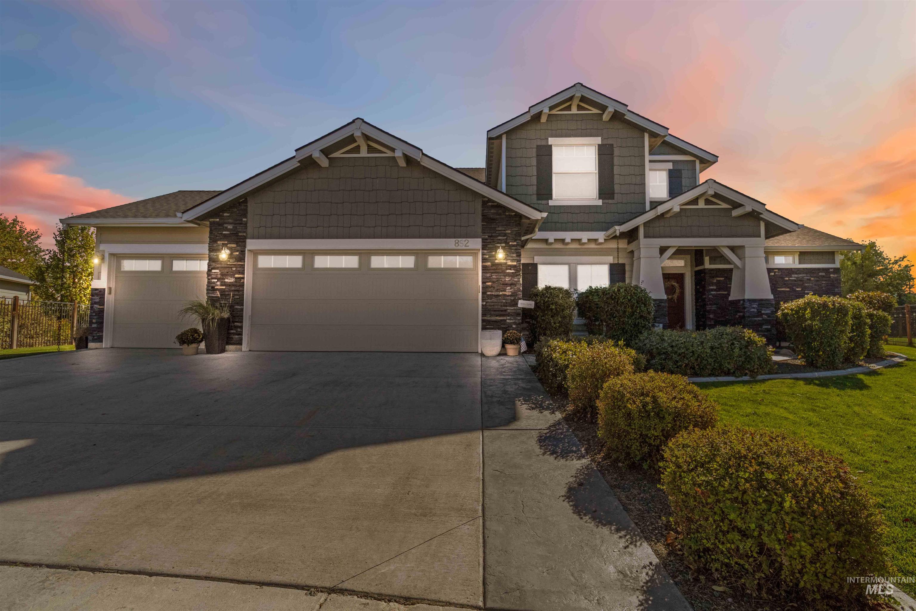 Craftsman inspired home with a garage, stone siding, driveway, and a yard