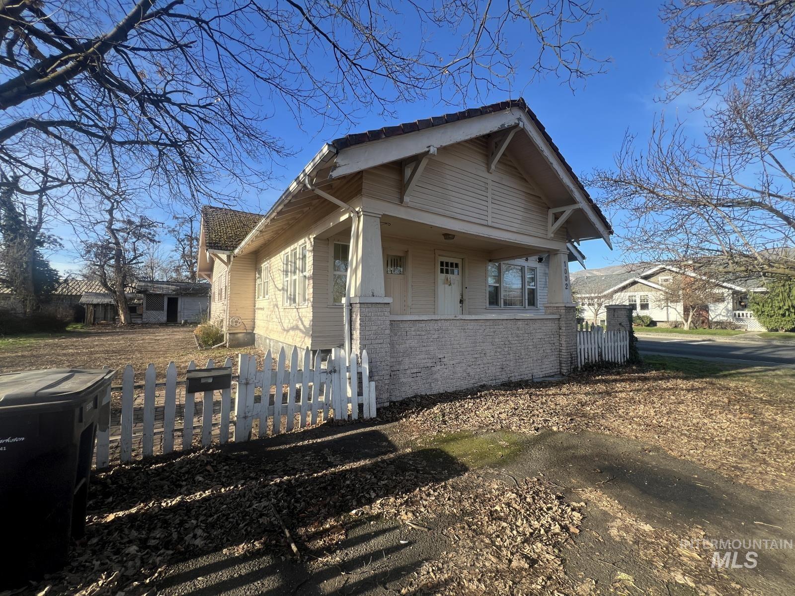 Bungalow-style home featuring brick siding and a fenced front yard