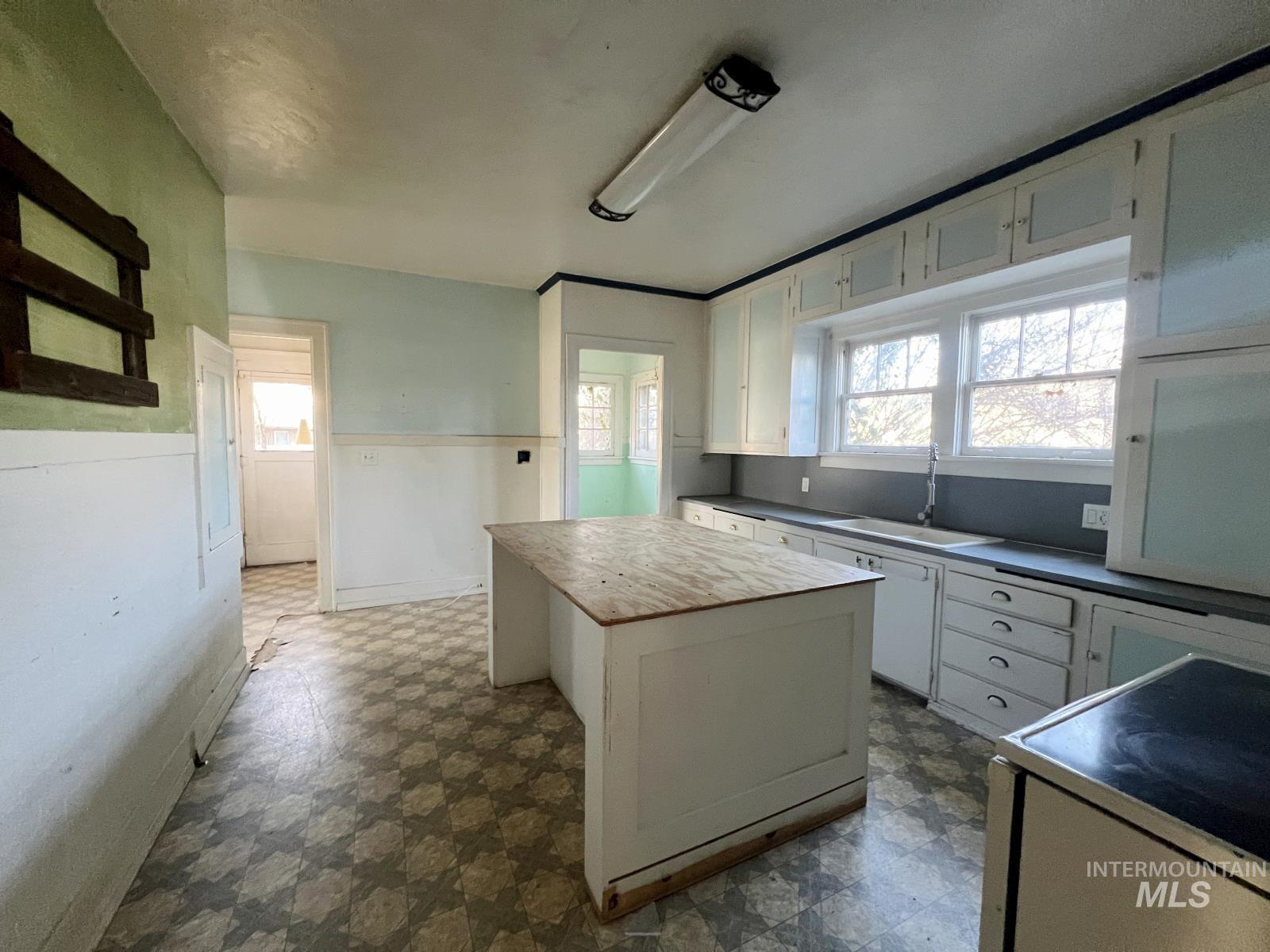 Kitchen featuring dark flooring, white cabinetry, electric stove, a kitchen island, and plenty of natural light