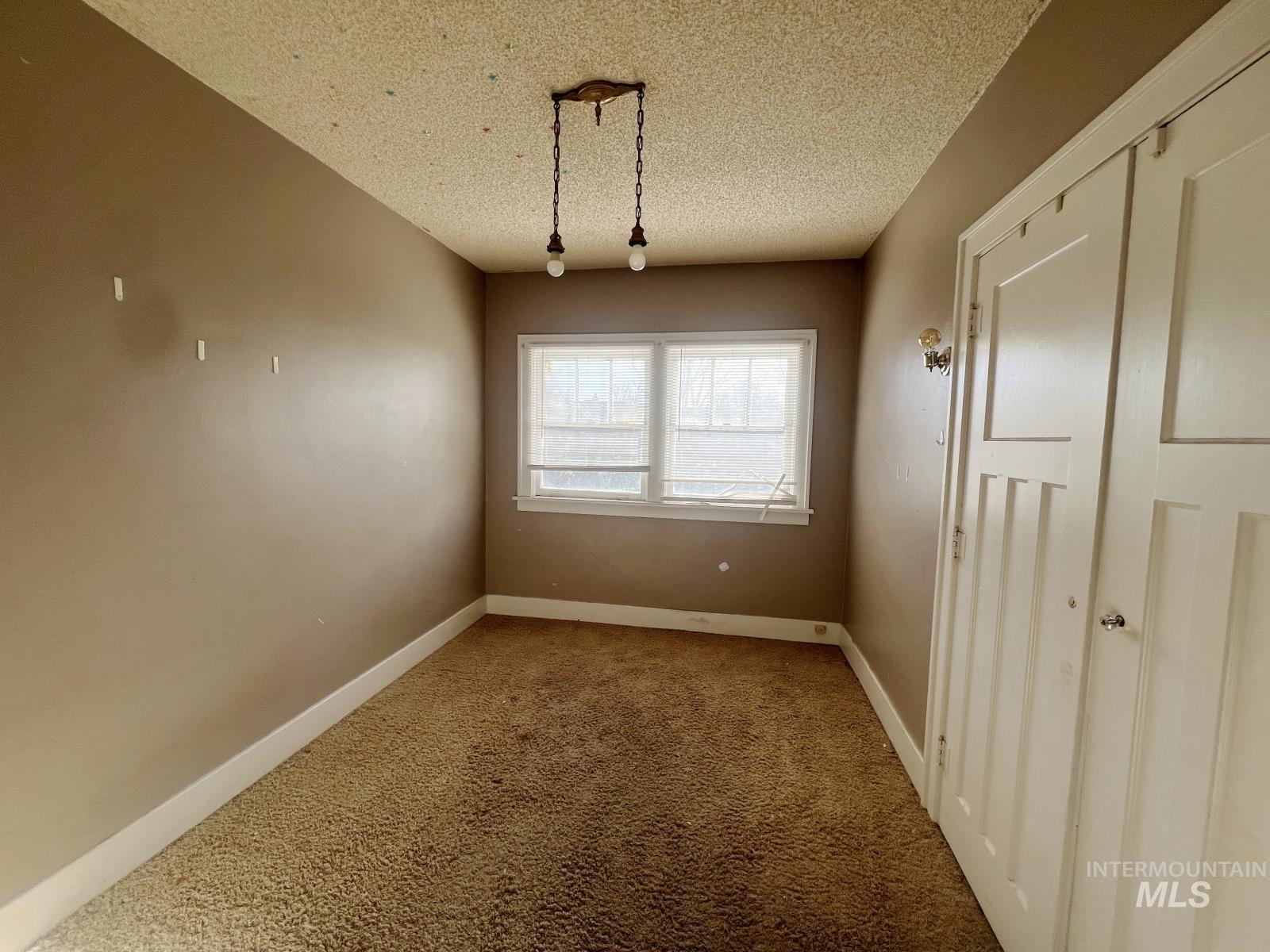 Unfurnished dining area with carpet floors and a textured ceiling