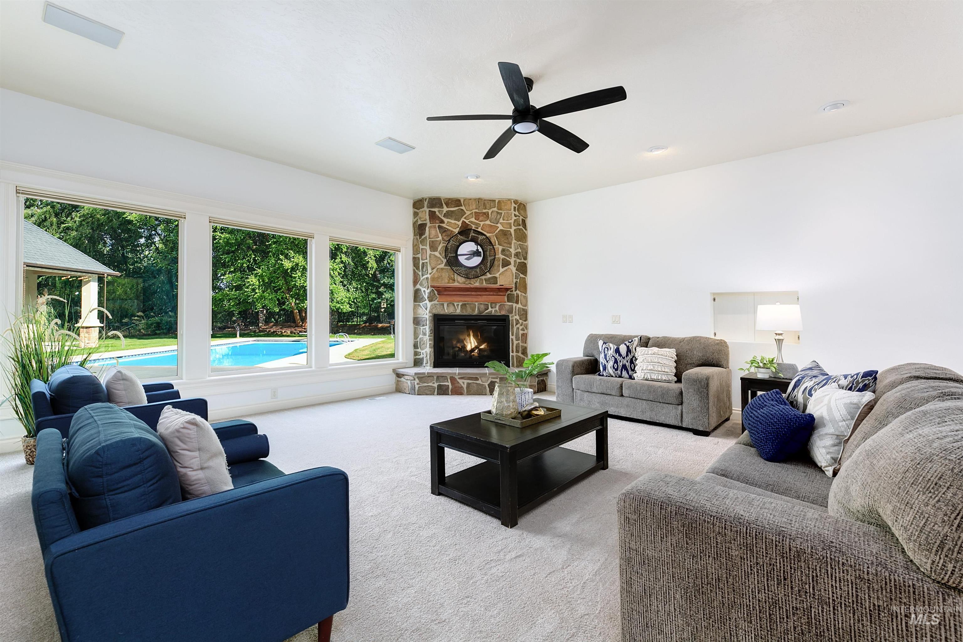 Living room featuring carpet flooring, a fireplace, and ceiling fan