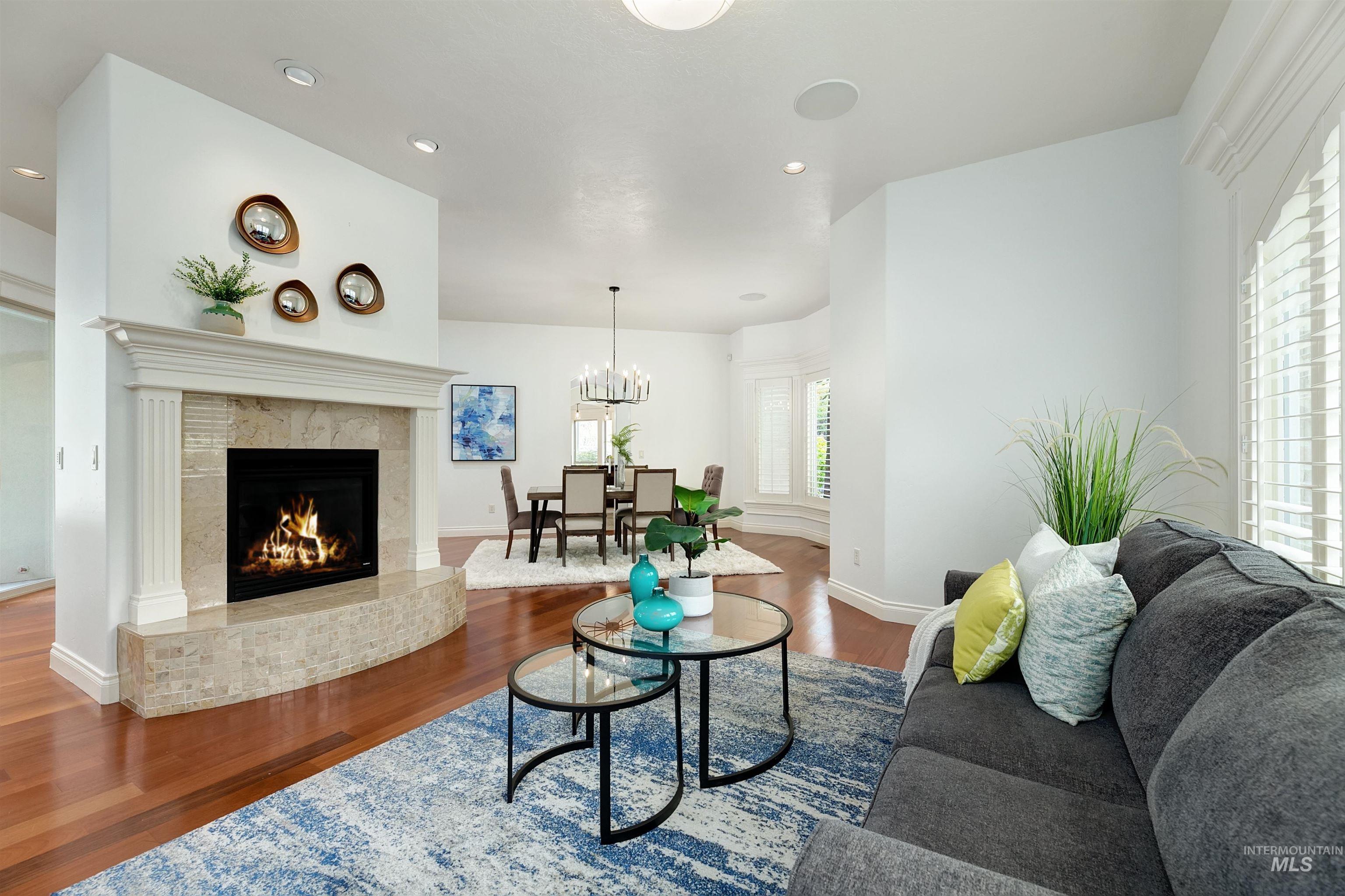 Living room with recessed lighting, wood finished floors, a premium fireplace, and a chandelier