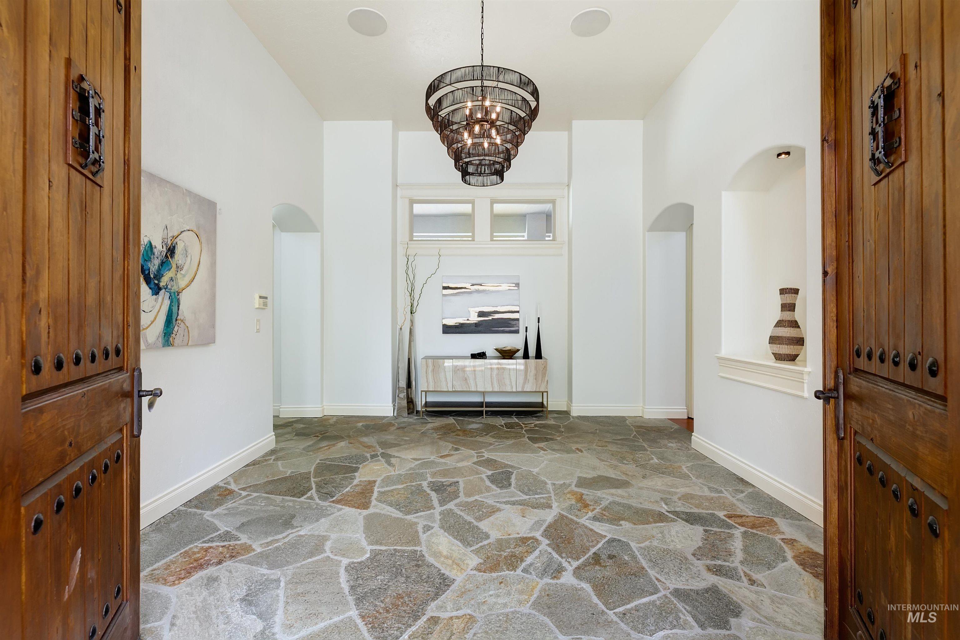 Entrance foyer featuring stone floors, arched walkways, and a chandelier