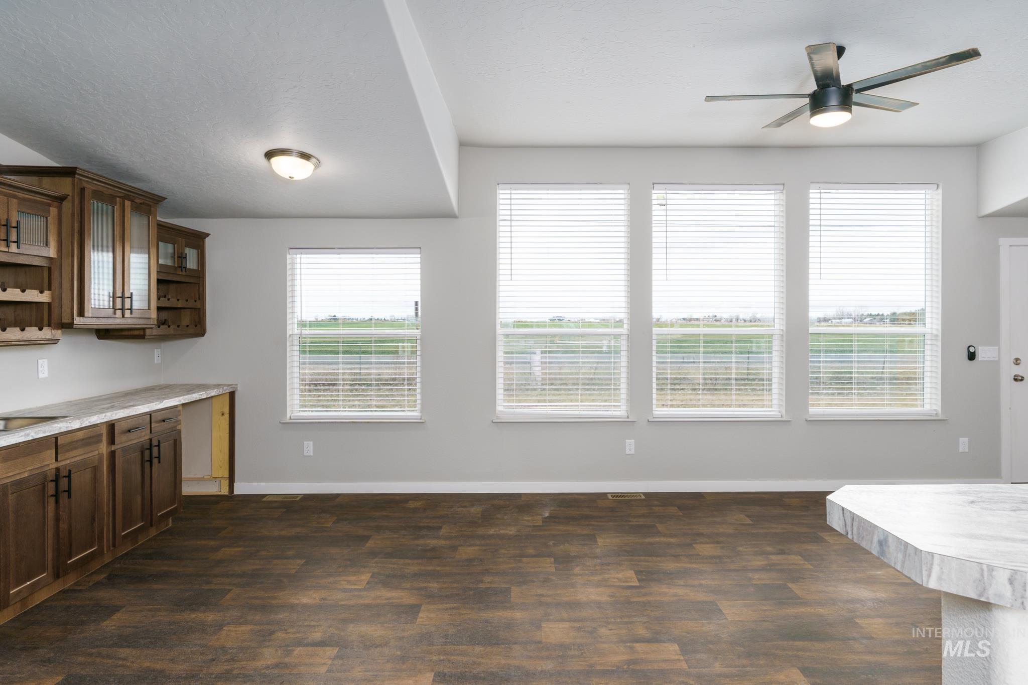 Unfurnished dining area with dark wood-style flooring and ceiling fan