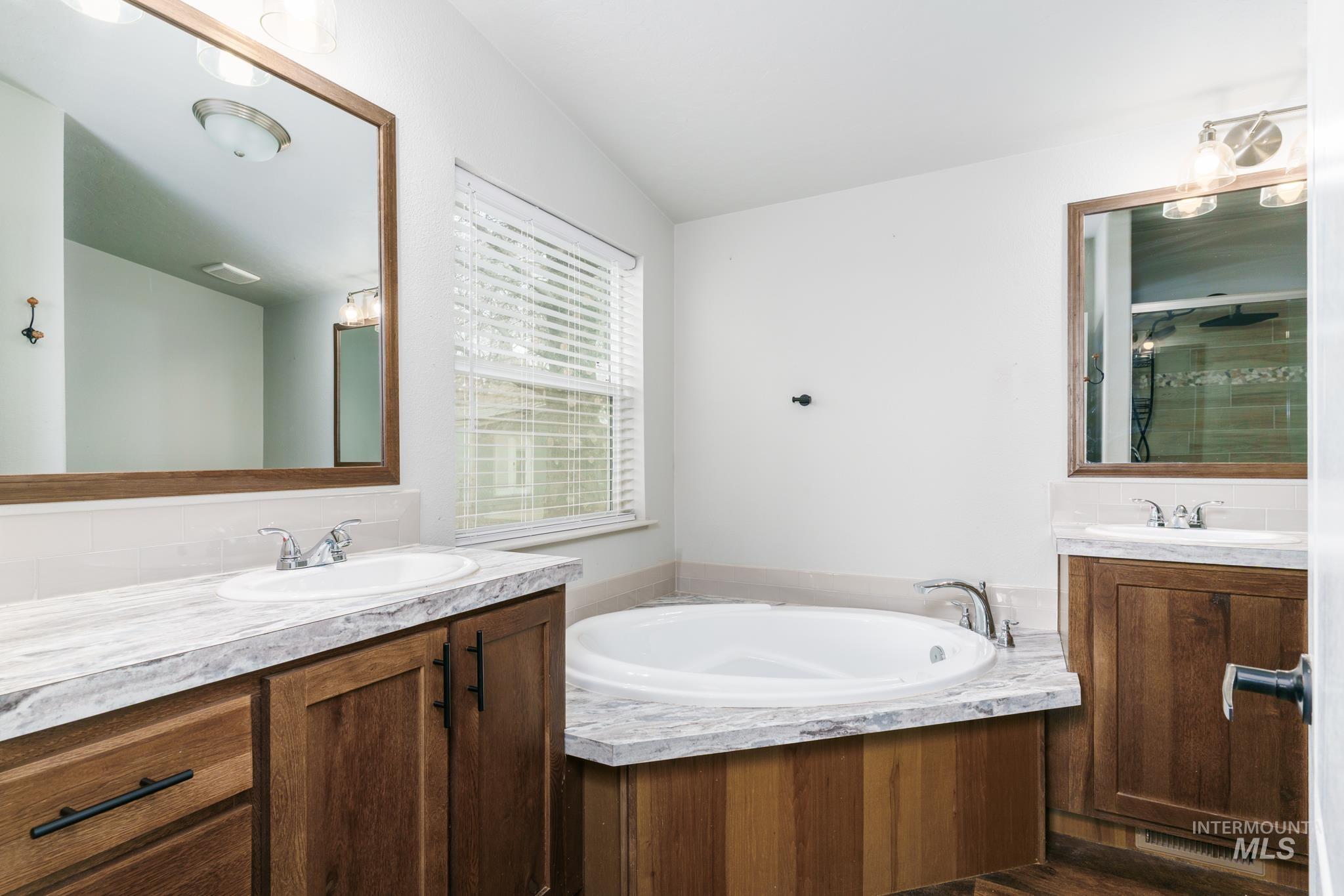 Full bath featuring two vanities, a bath, and a shower stall