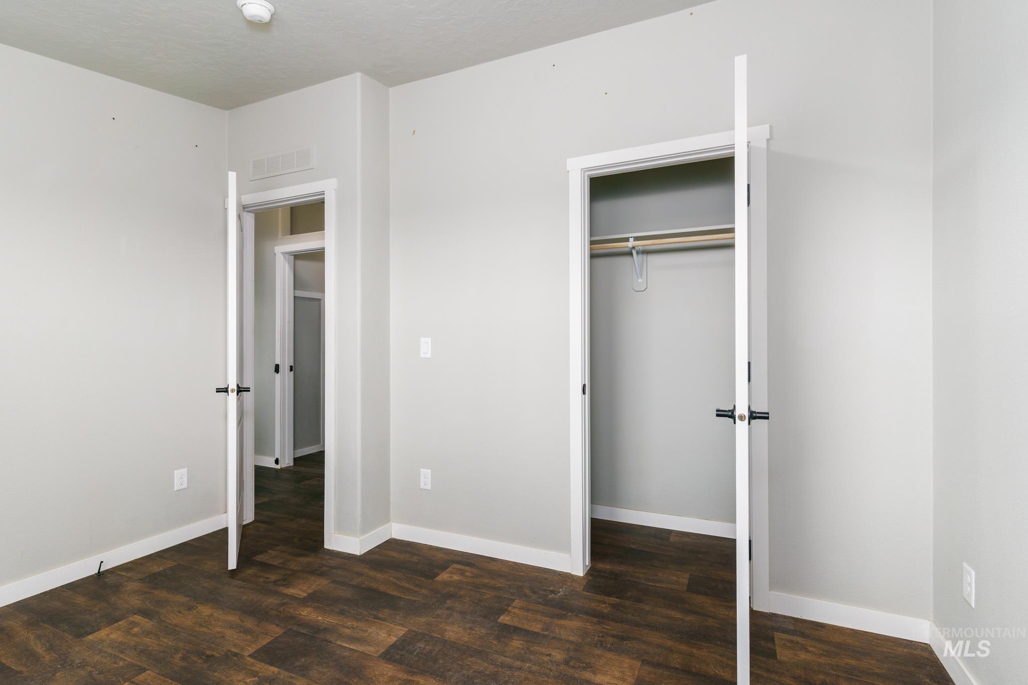 Unfurnished bedroom with dark wood-style floors, a closet, and a textured ceiling