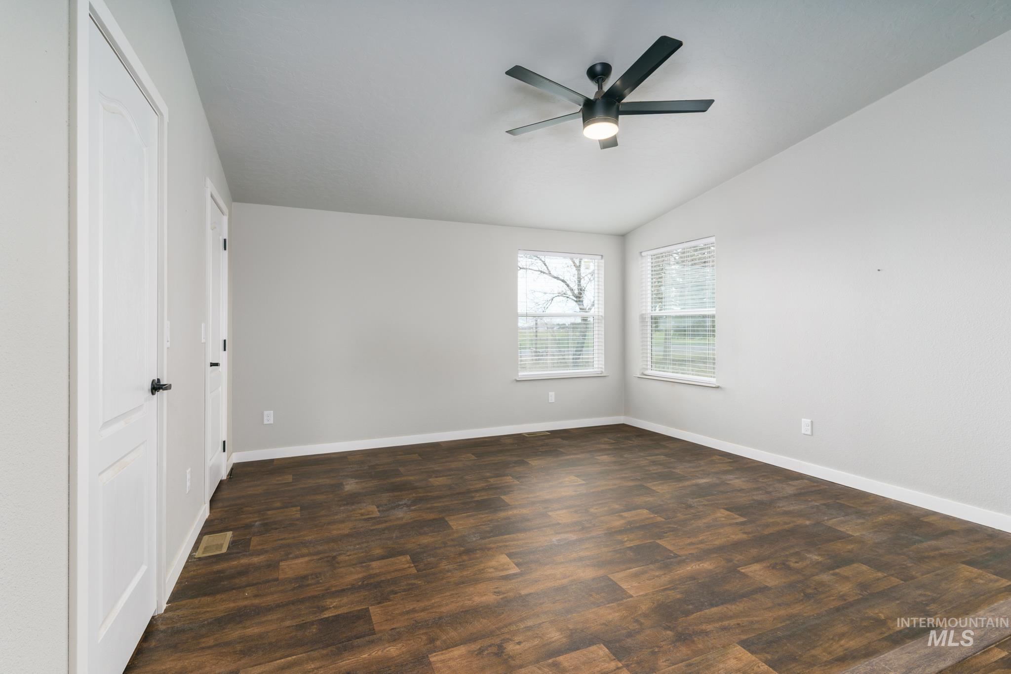 Unfurnished bedroom featuring a closet, a ceiling fan, dark wood-type flooring, and vaulted ceiling