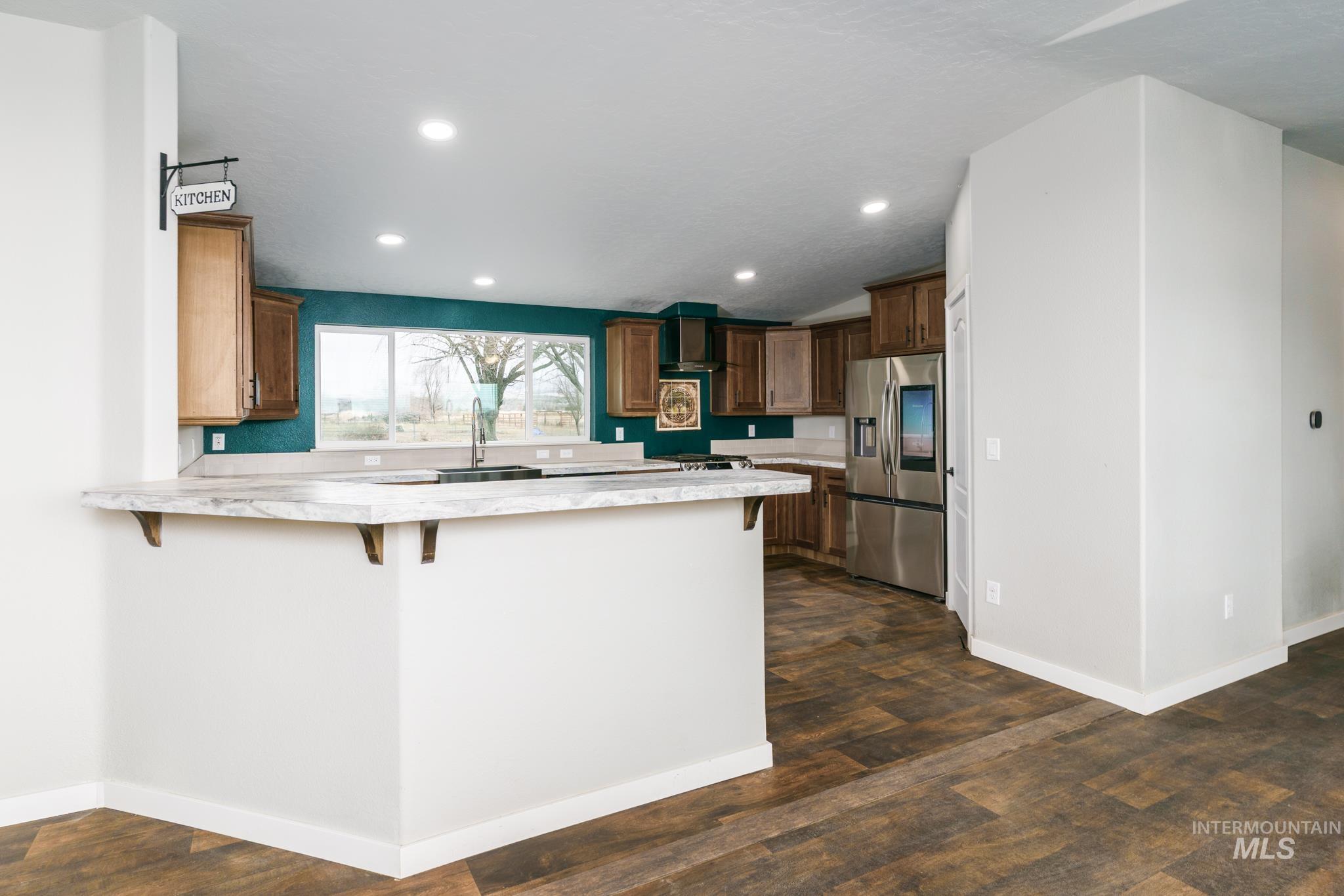 Kitchen featuring light countertops, a breakfast bar, stainless steel fridge, a peninsula, and recessed lighting