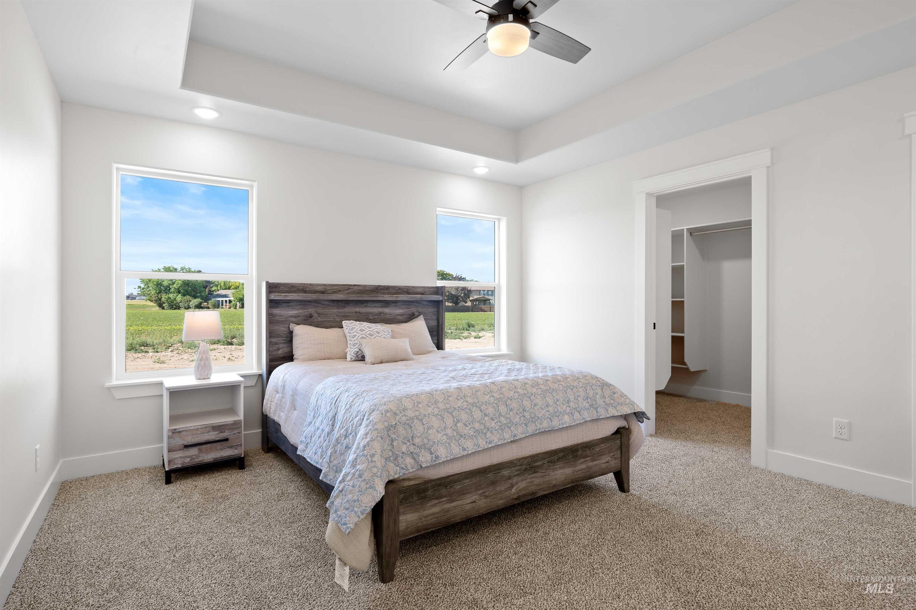 Bedroom with light carpet, a spacious closet, recessed lighting, a ceiling fan, and a tray ceiling