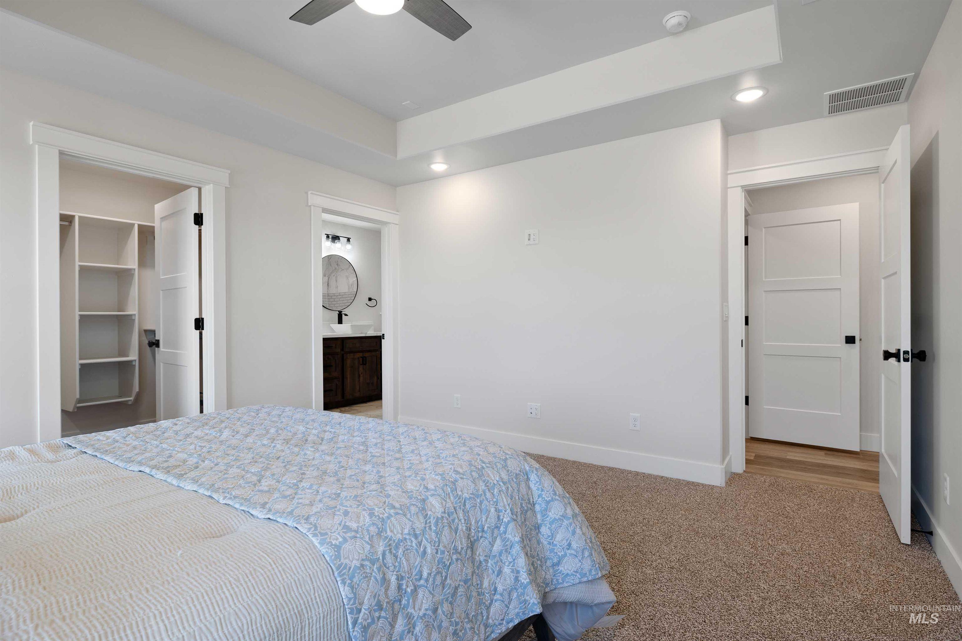 Carpeted bedroom with a walk in closet, recessed lighting, connected bathroom, and ceiling fan