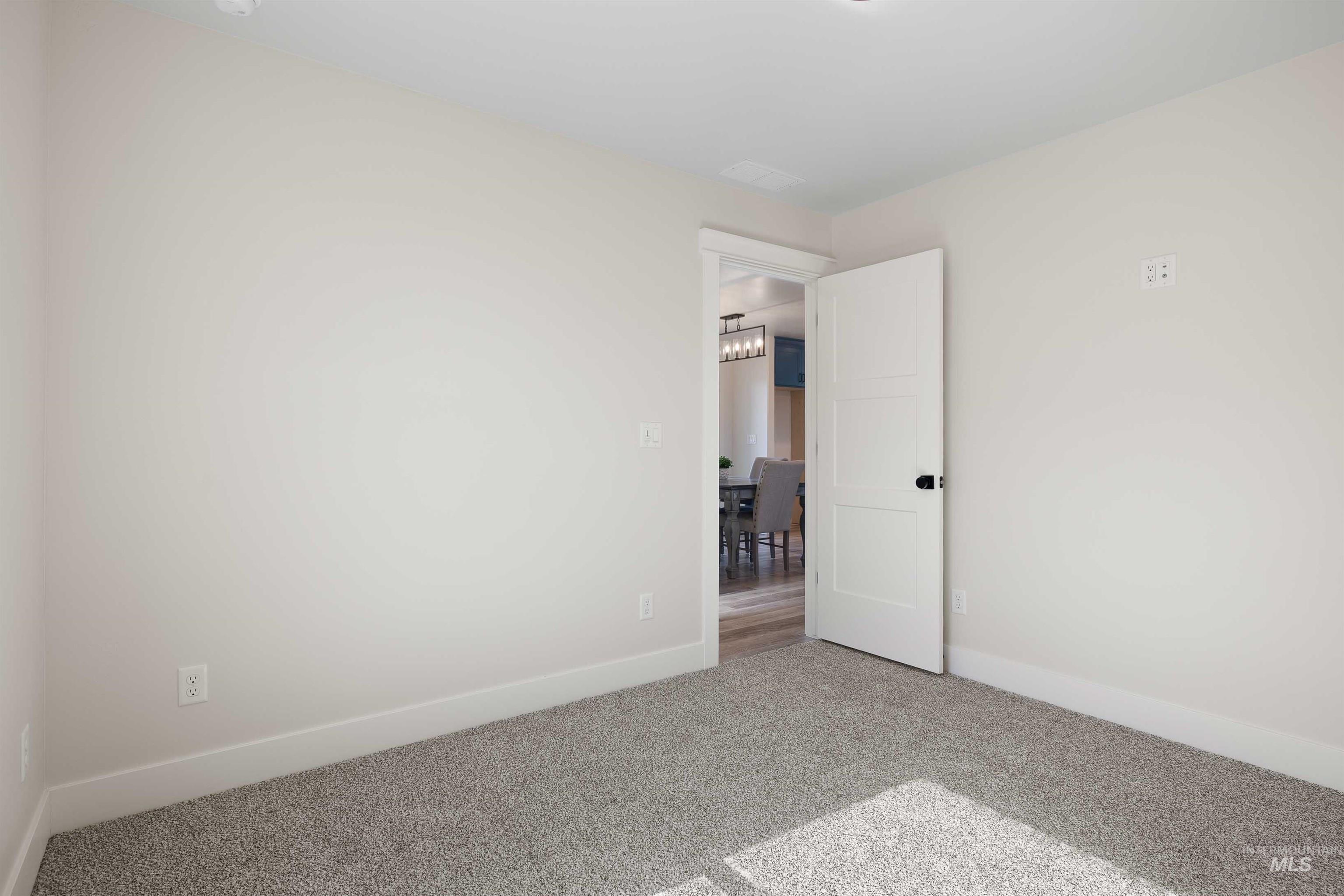 Carpeted spare room featuring baseboards