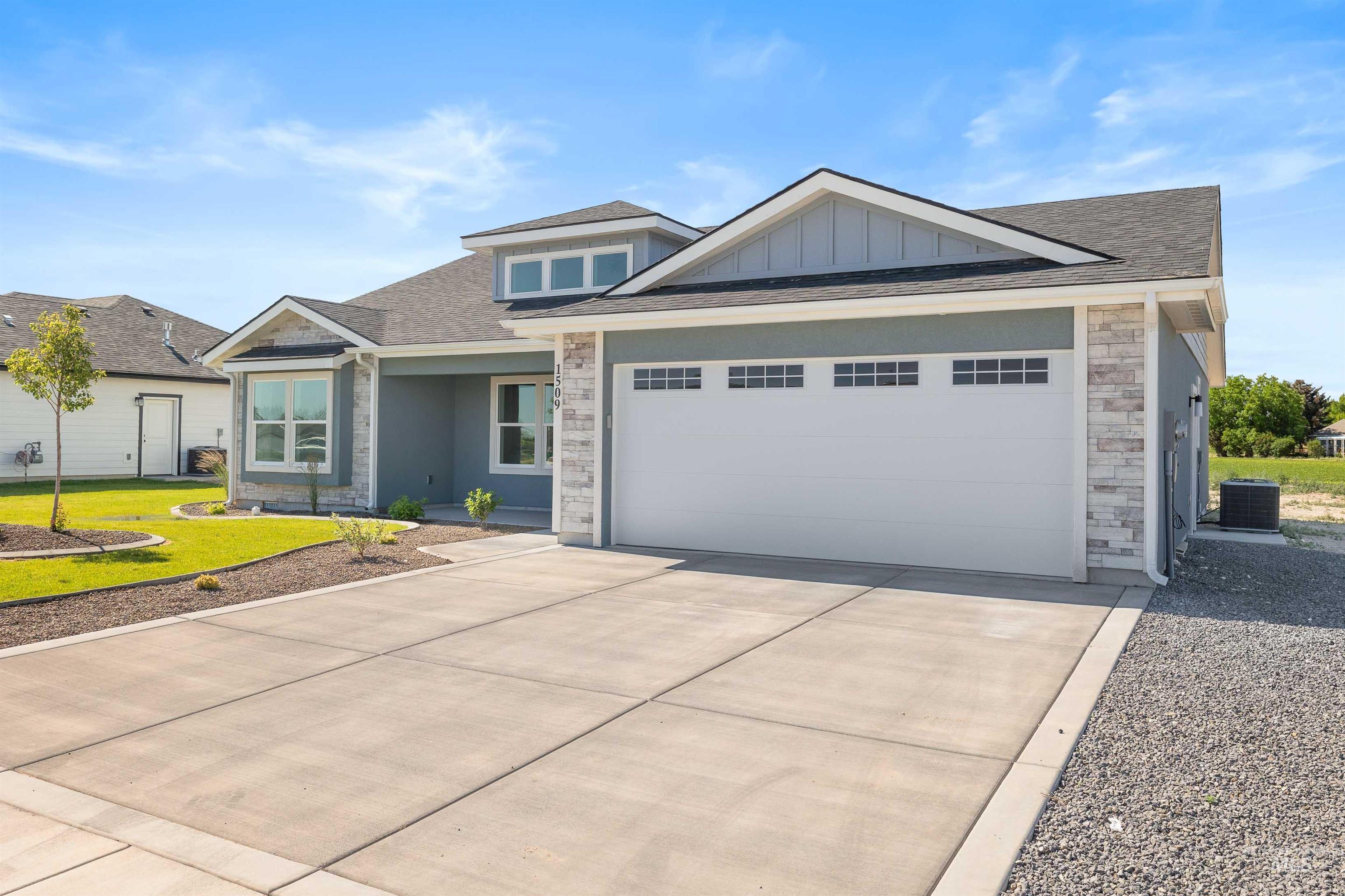 View of front of property with stone siding, concrete driveway, an attached garage, a front yard, and roof with shingles