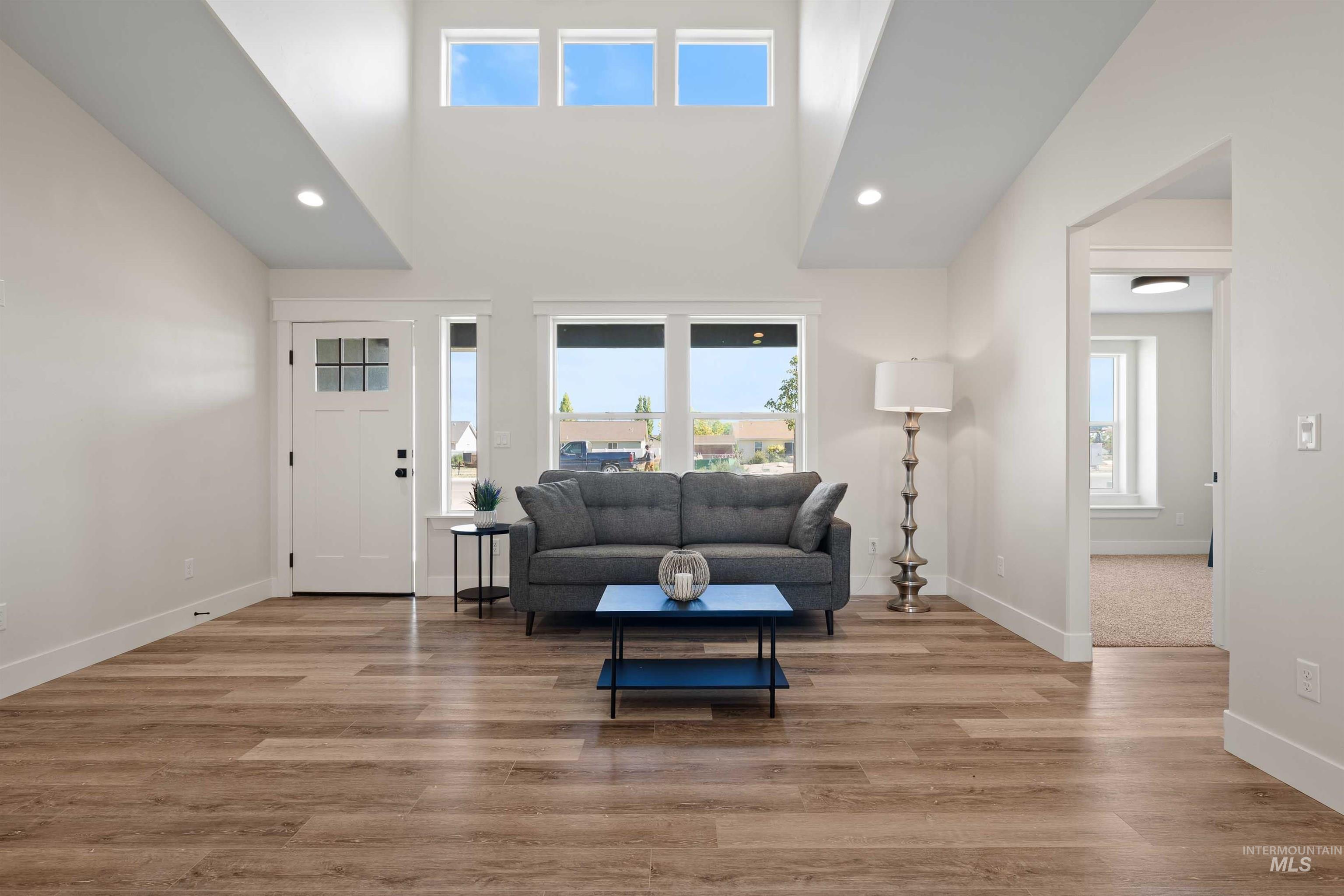 Living room with recessed lighting, wood finished floors, and a towering ceiling