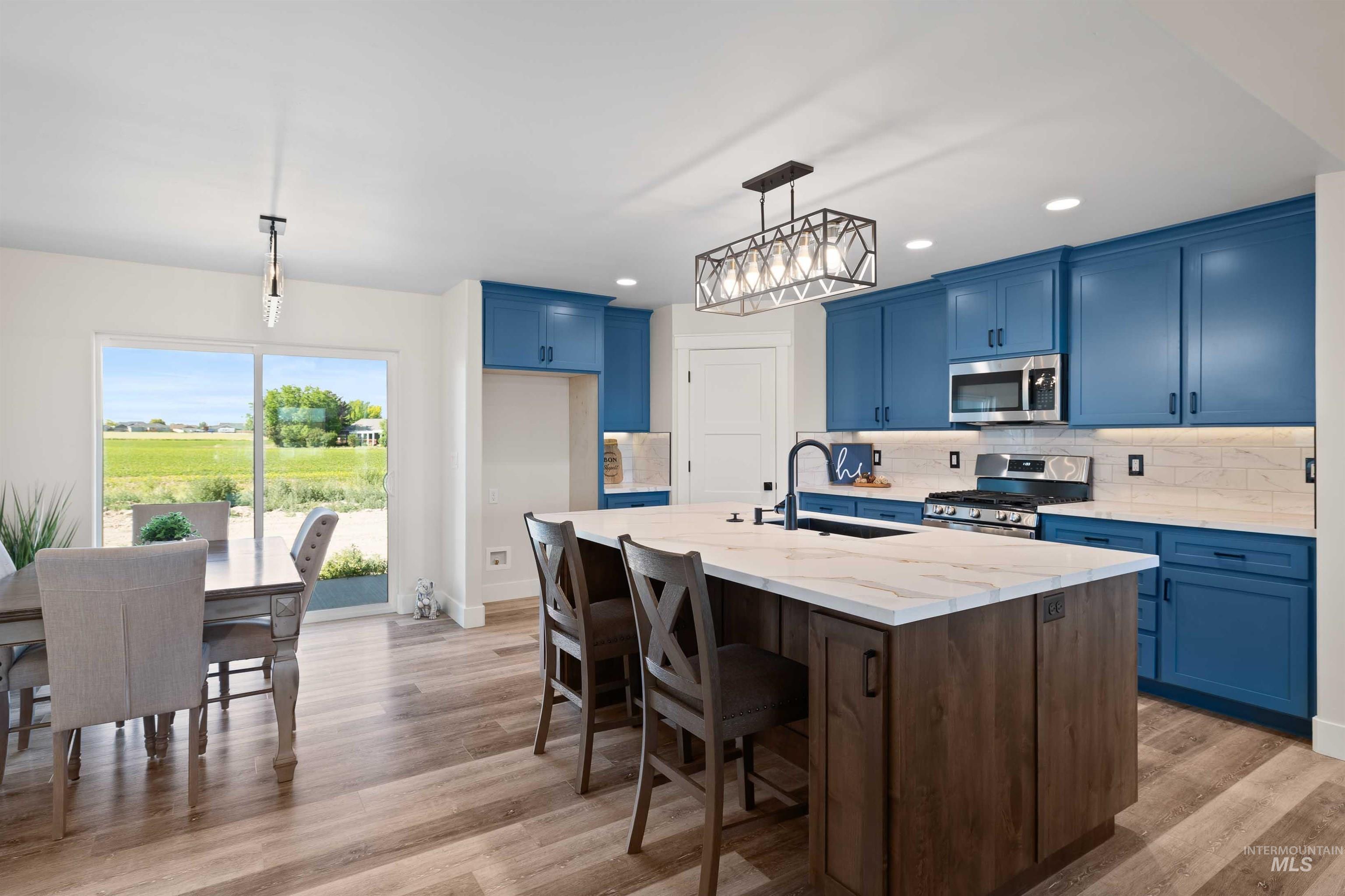 Kitchen featuring stainless steel appliances, blue cabinetry, light wood-type flooring, decorative backsplash, and recessed lighting
