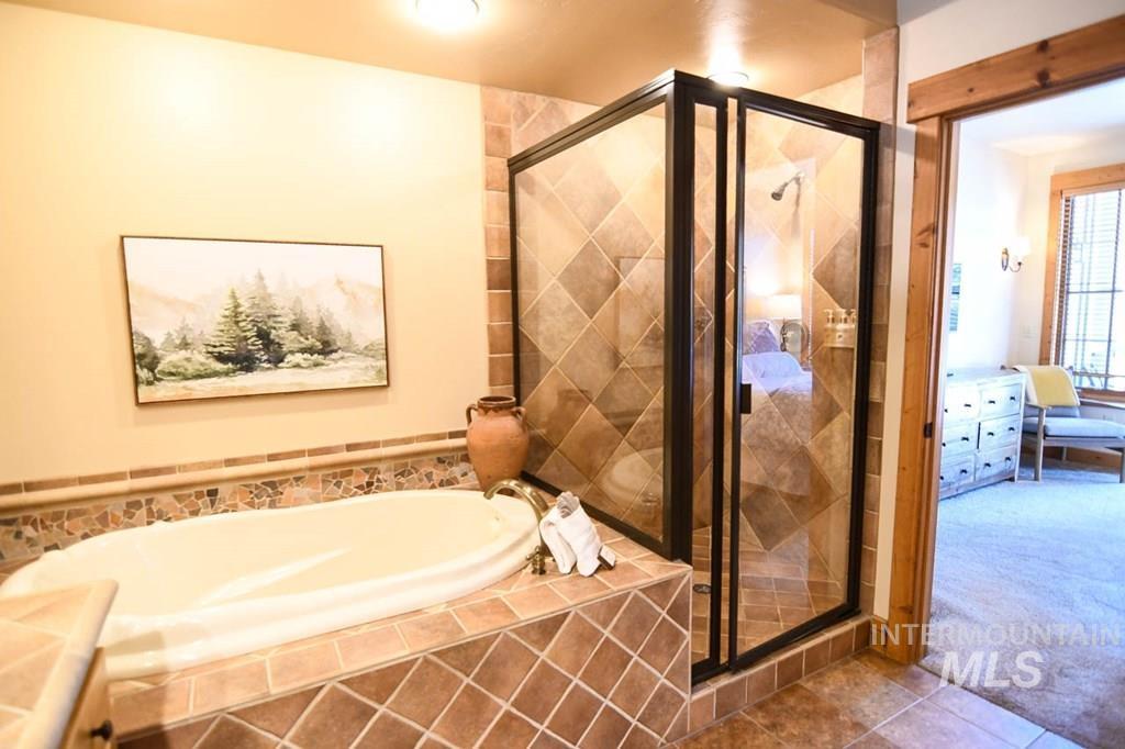 Bathroom with a bath, ensuite bath, a stall shower, carpet floors, and tile patterned floors