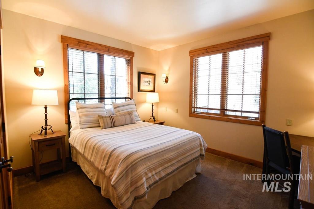 Bedroom with multiple windows, dark colored carpet, and a desk