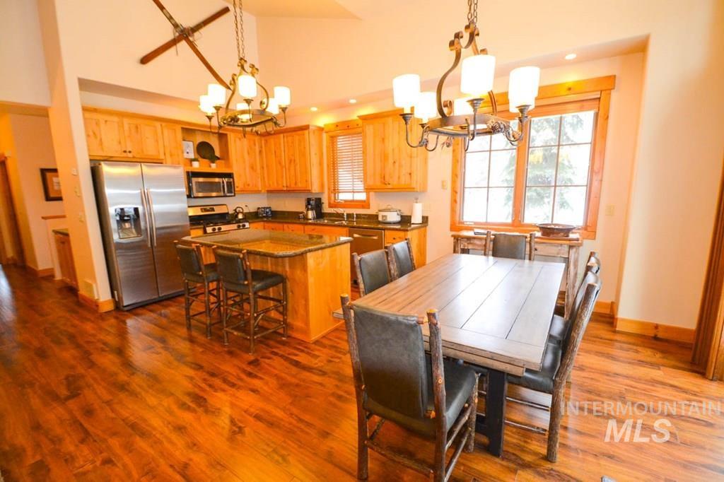 Dining room featuring a chandelier, plenty of natural light, dark wood finished floors, recessed lighting, and high vaulted ceiling